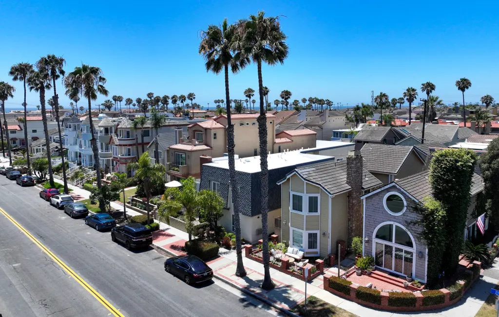 Homes along 21st Street in Huntington Beach, California, with palm trees and a clear sky overhead.