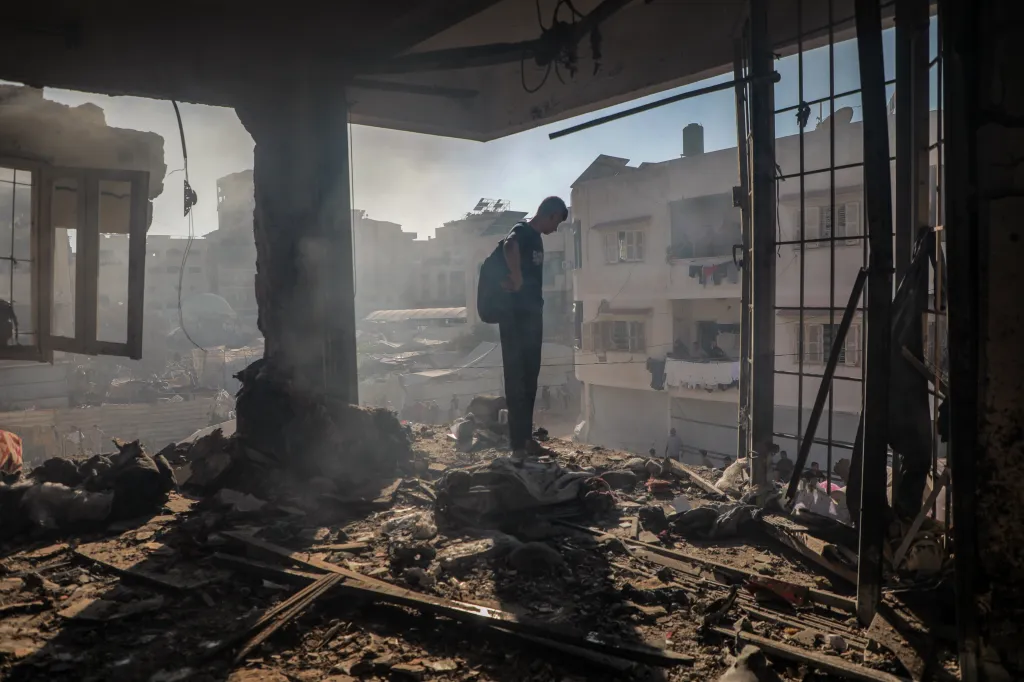 A Palestinian man standing amidst the rubble of a destroyed residential apartment in Gaza City.