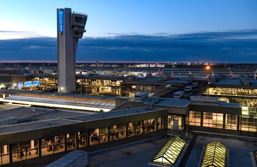 Travelers waiting in line inside the Philadelphia International Airport at dusk.