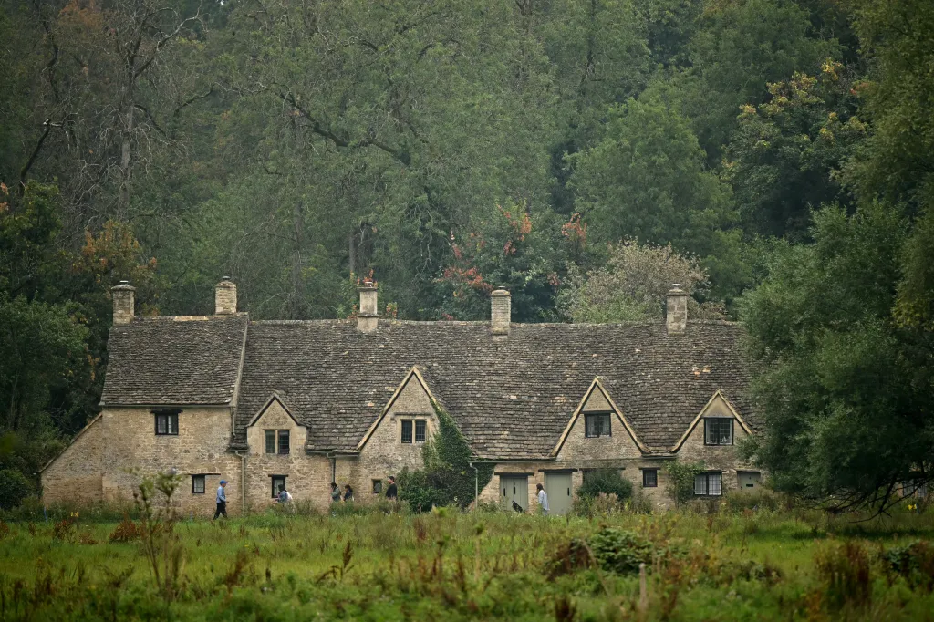 People walk past Arlington Row Bibury in the Cotswolds region of England.