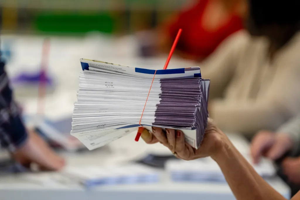 An election worker holds a stack of mail-in ballots.
