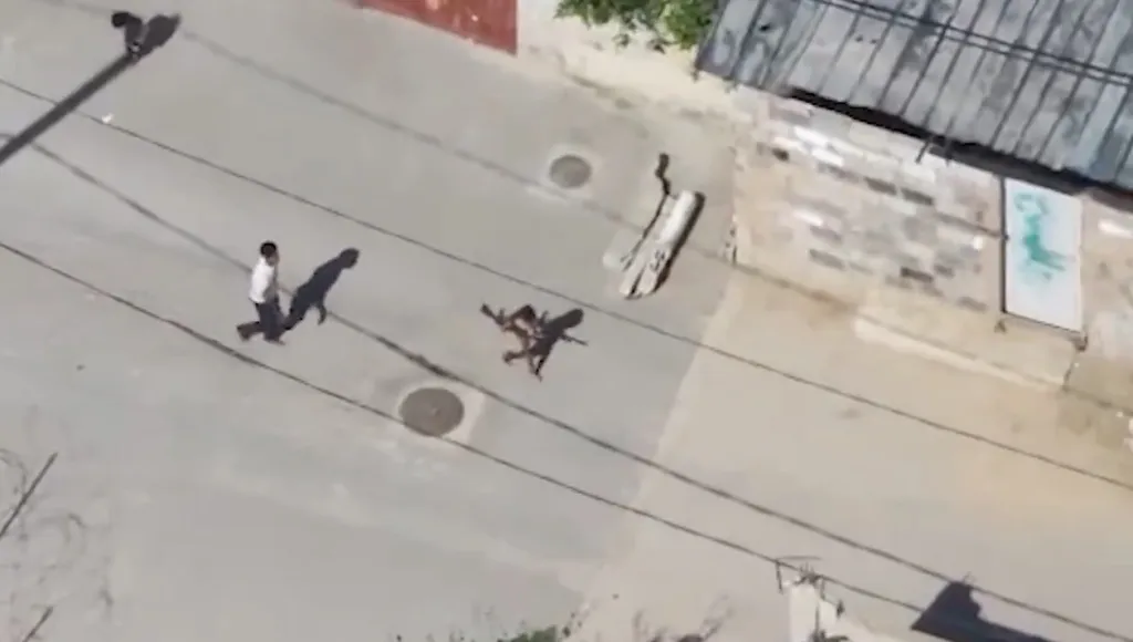 Aerial view of a street in Gaza showing a terrorist and child transferring weapons into a civilian home.