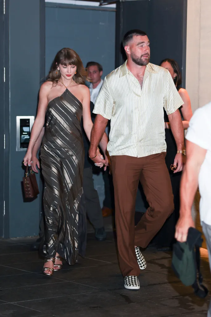 Taylor Swift and Travis Kelce holding hands while arriving at Ambassadors Clubhouse for dinner.