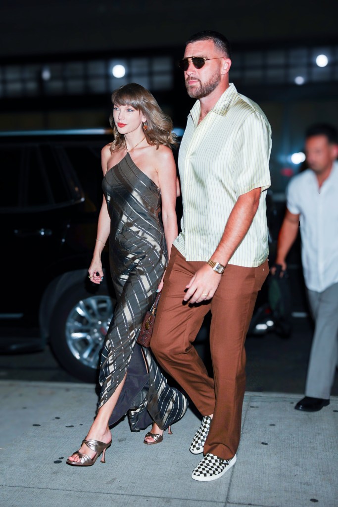 Taylor Swift in a metallic striped dress and Travis Kelce in a striped shirt and brown pants, walking side-by-side.