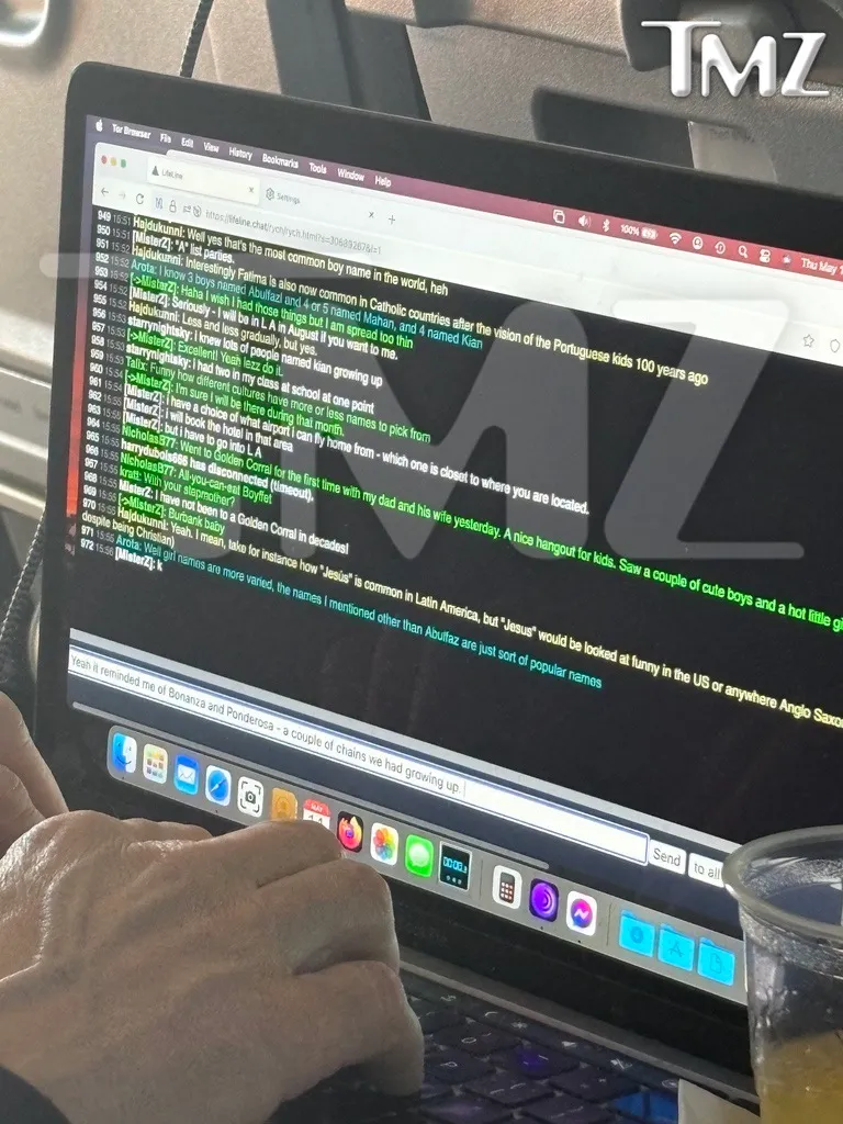 A person typing on a MacBook laptop, displaying a chat conversation on the screen.