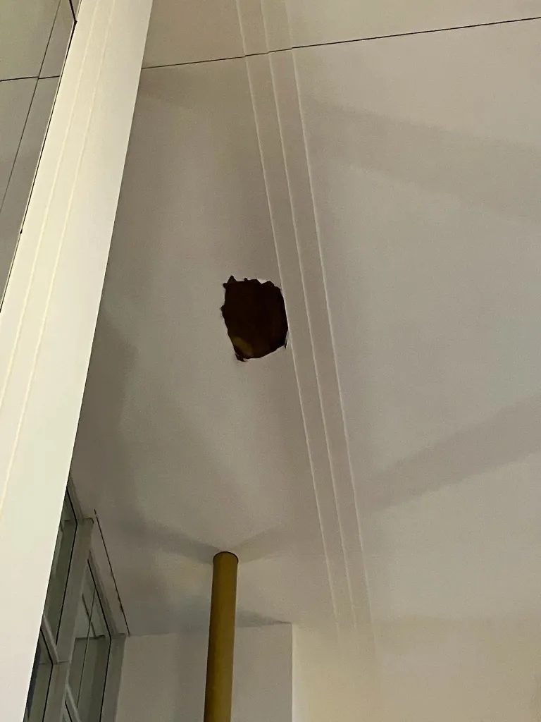 A large hole in a white ceiling caused by a collapse.