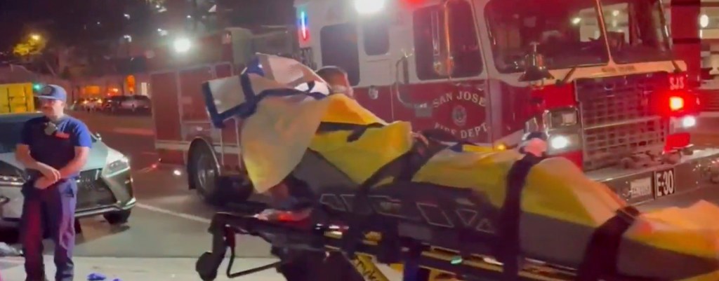 A person on a stretcher is being attended to by emergency personnel next to a San Jose Fire Department truck.