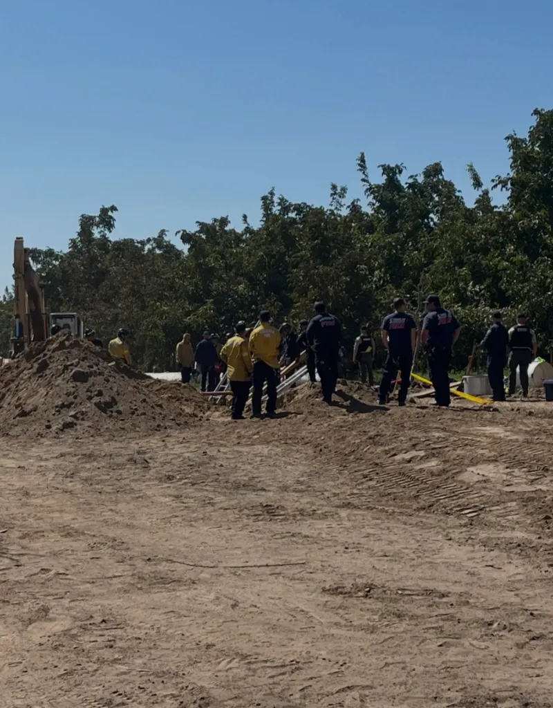 Emergency personnel at the scene of a trench collapse where a worker was trapped and later died.