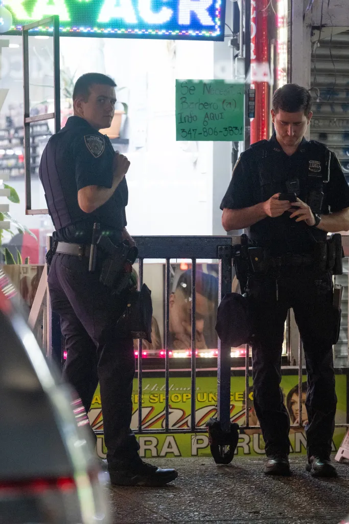 Two NYPD officers patrol near a storefront with a 