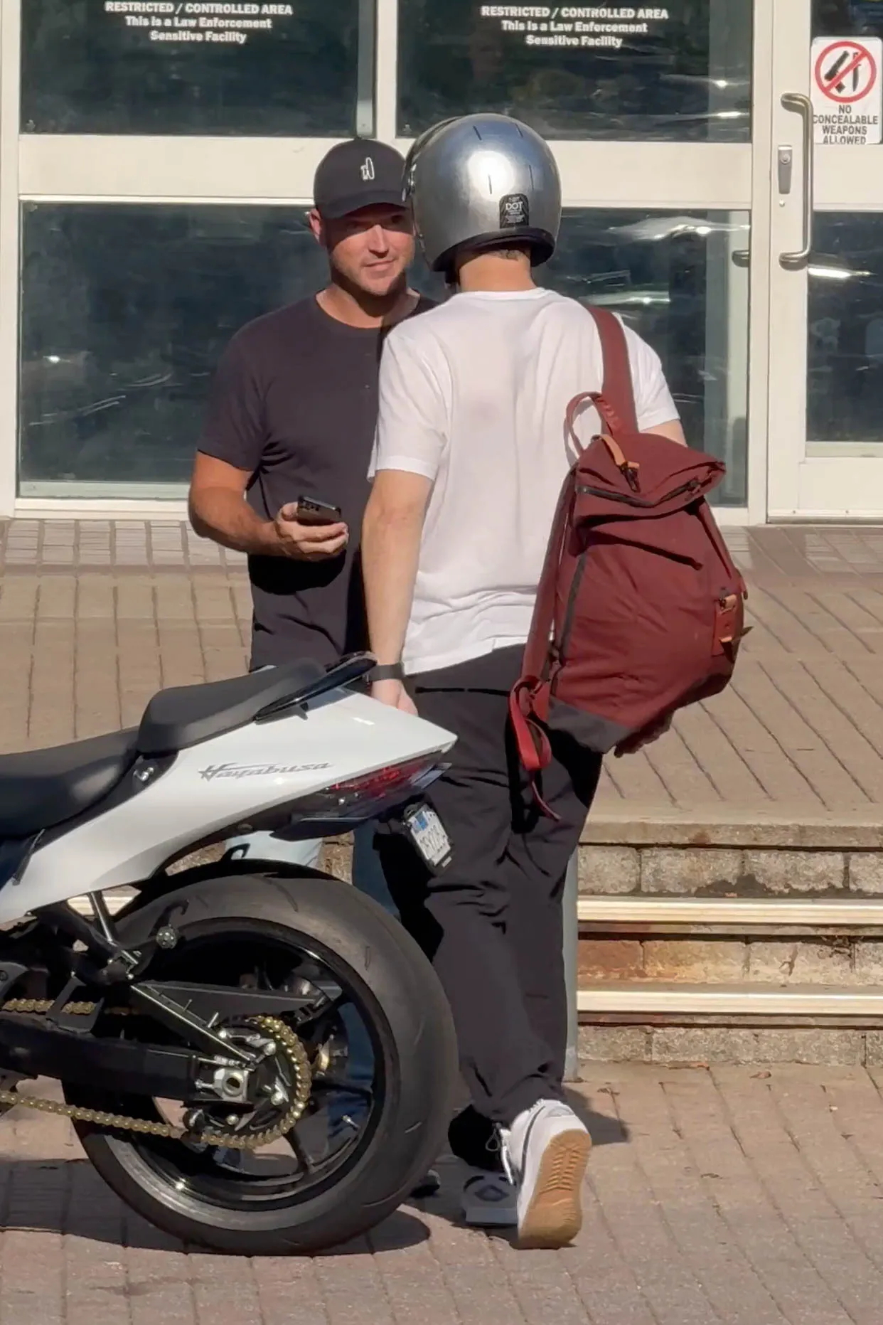 Zach Hickerson leaving jail after being arrested for a fight in Greenville, next to a white motorcycle.