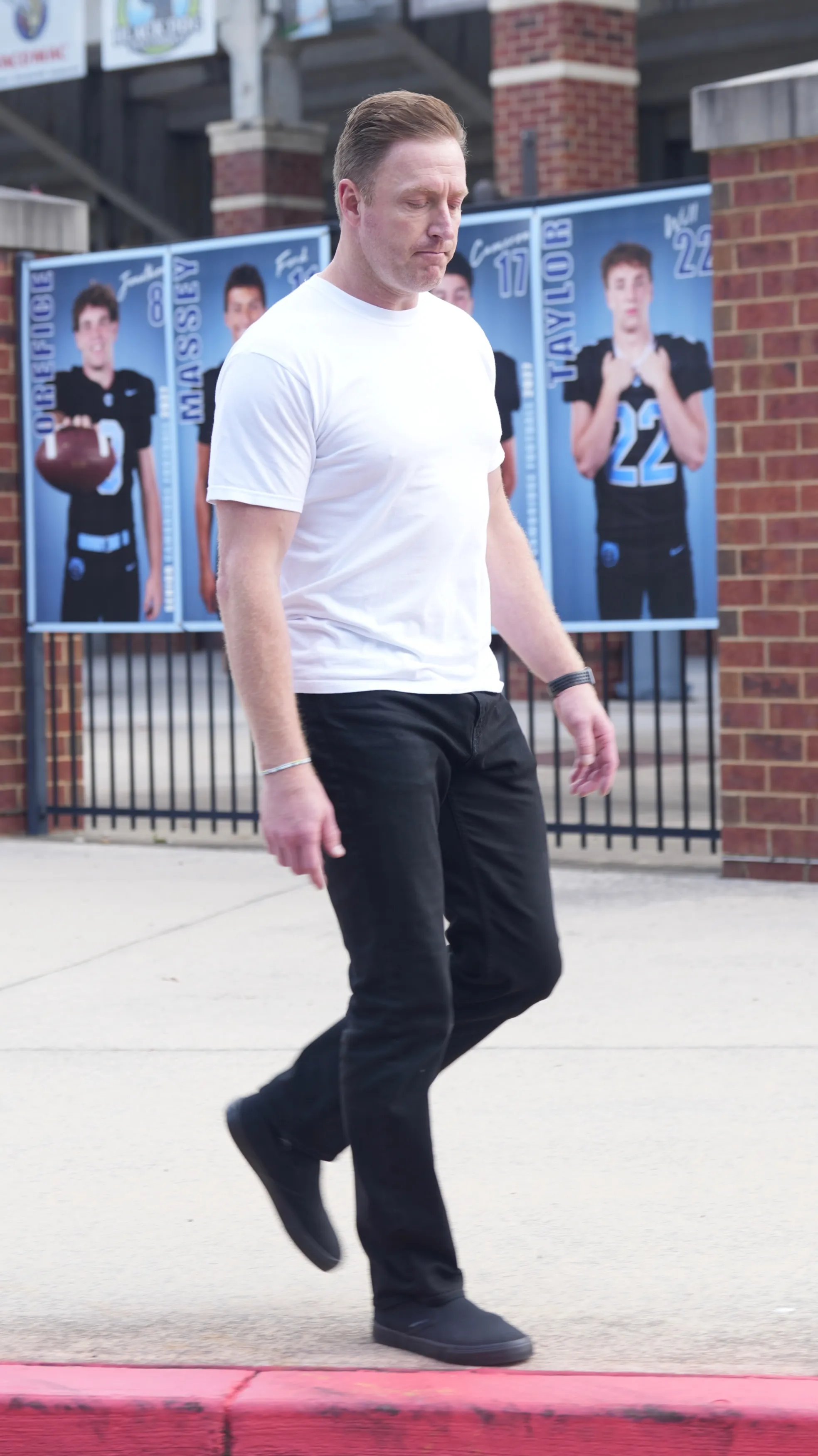Kroy Biermann walking outside a building with images of football players in the background.