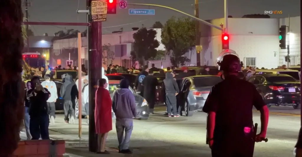 Police operation against illegal street racing, with many people and cars blocked at an intersection at night.