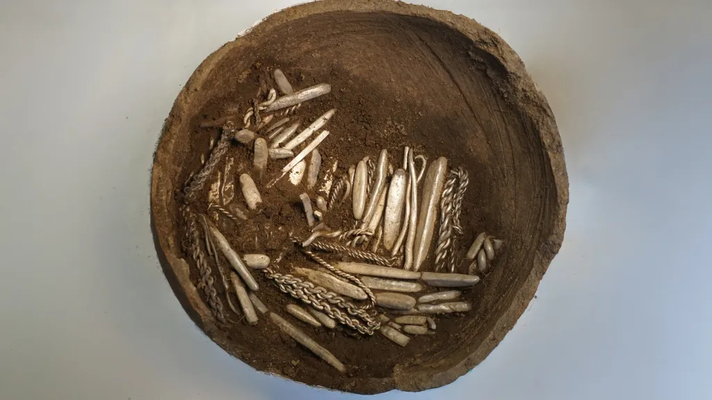 Viking silver hoard of around 700 objects, including bracelets, coins, and silver bars, in a clay vessel.