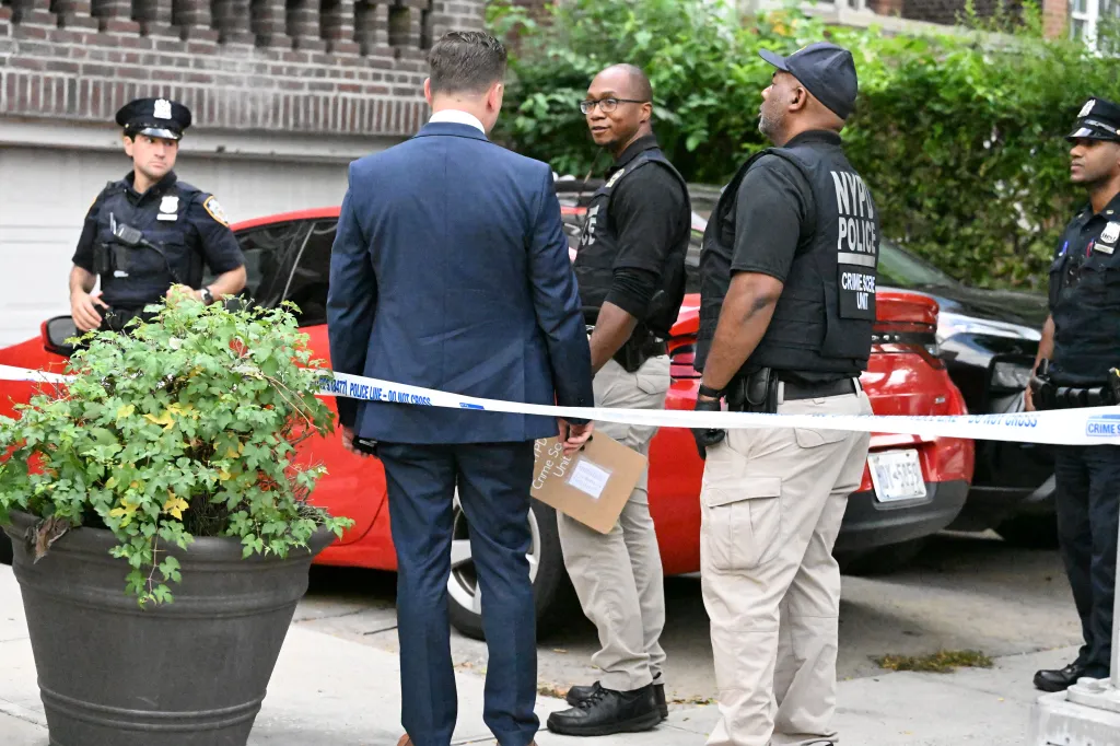 NYPD officers and a man in a suit stand behind 