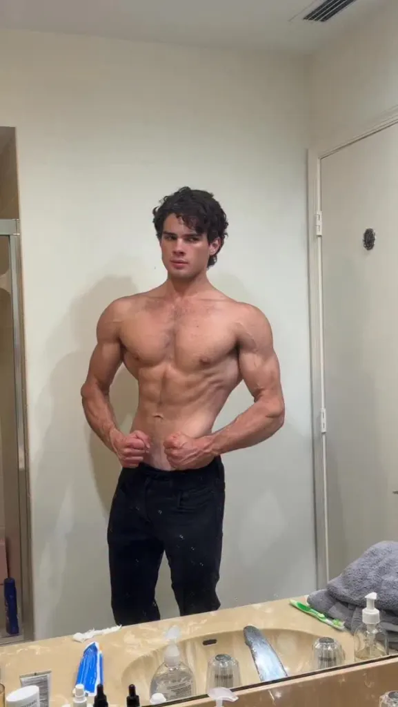 A muscular man posing in a bathroom mirror.