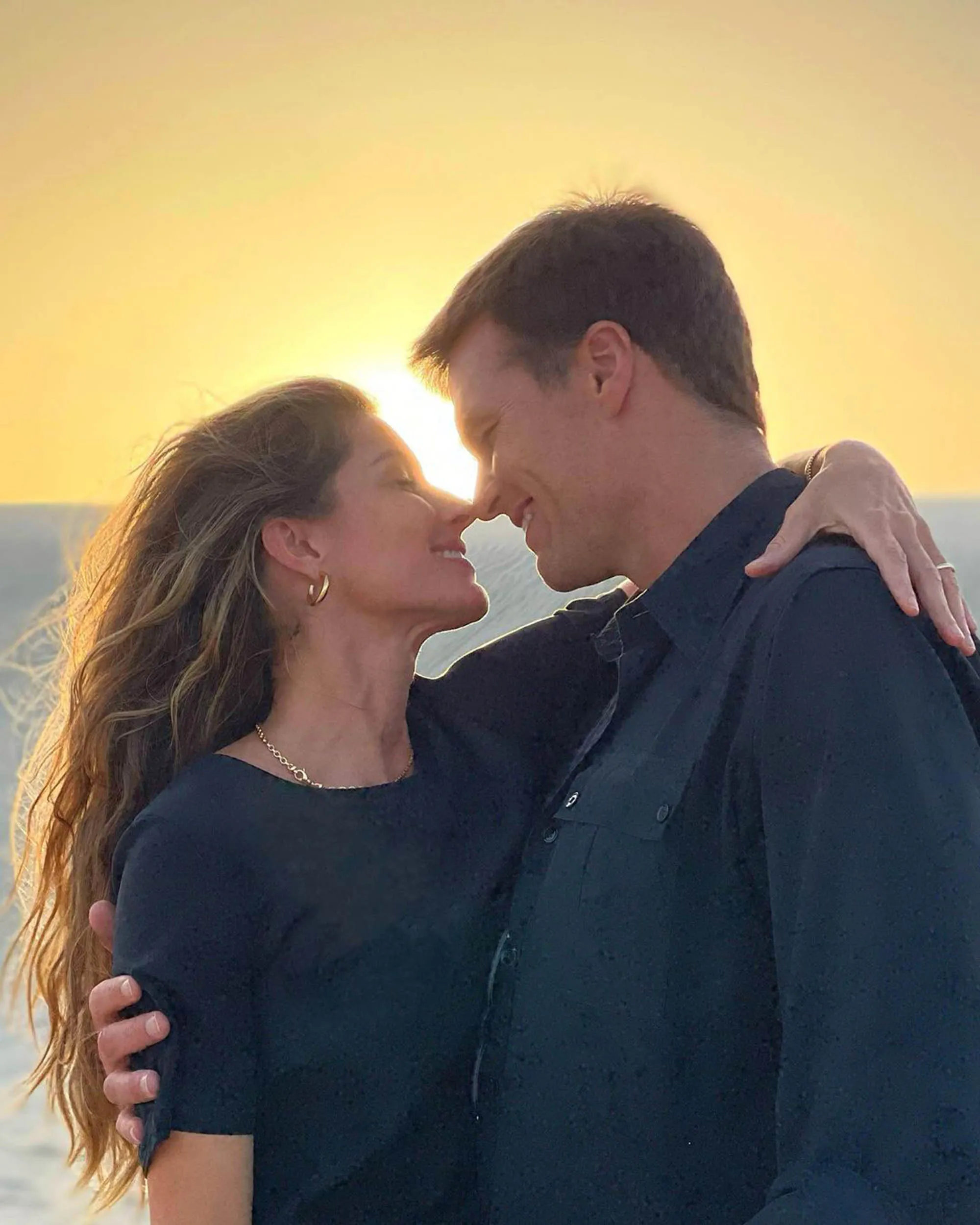 Tom Brady and Gisele Bündchen nose-to-nose against a sunset.