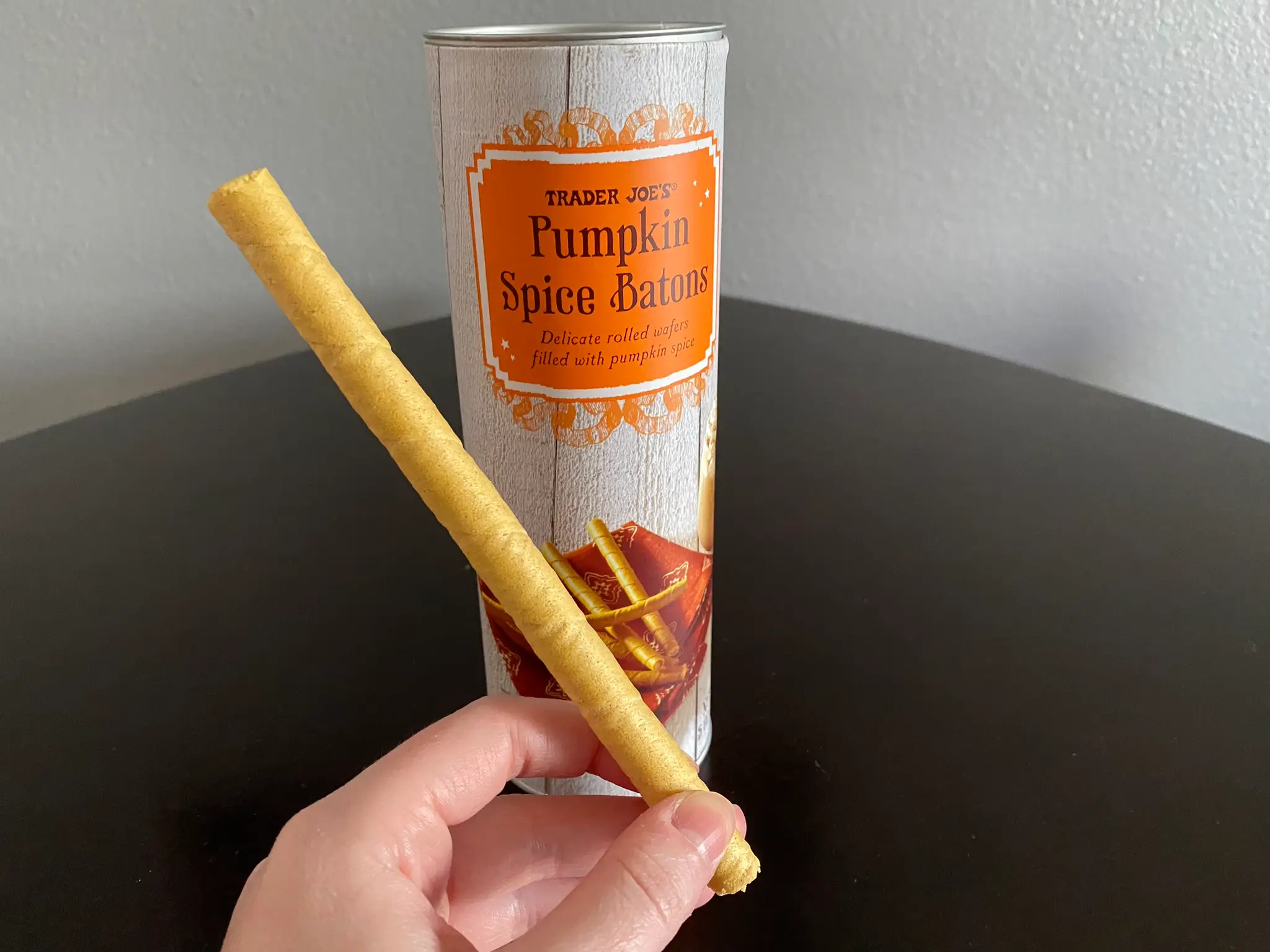 author holding pumpkin spice baton in front of jar of batons