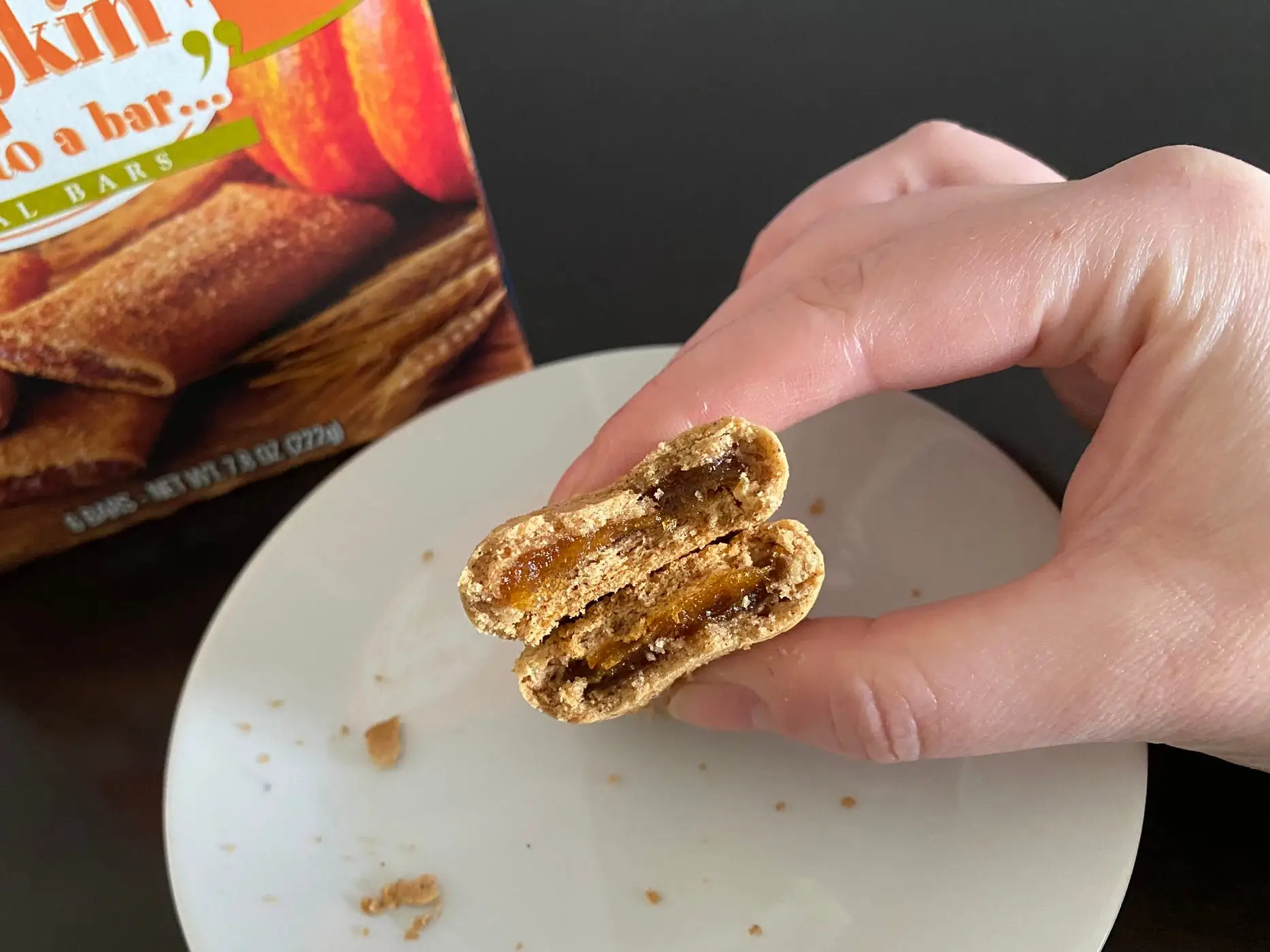 Trader Joe's pumpkin bar broken in half in author's hand above white plate