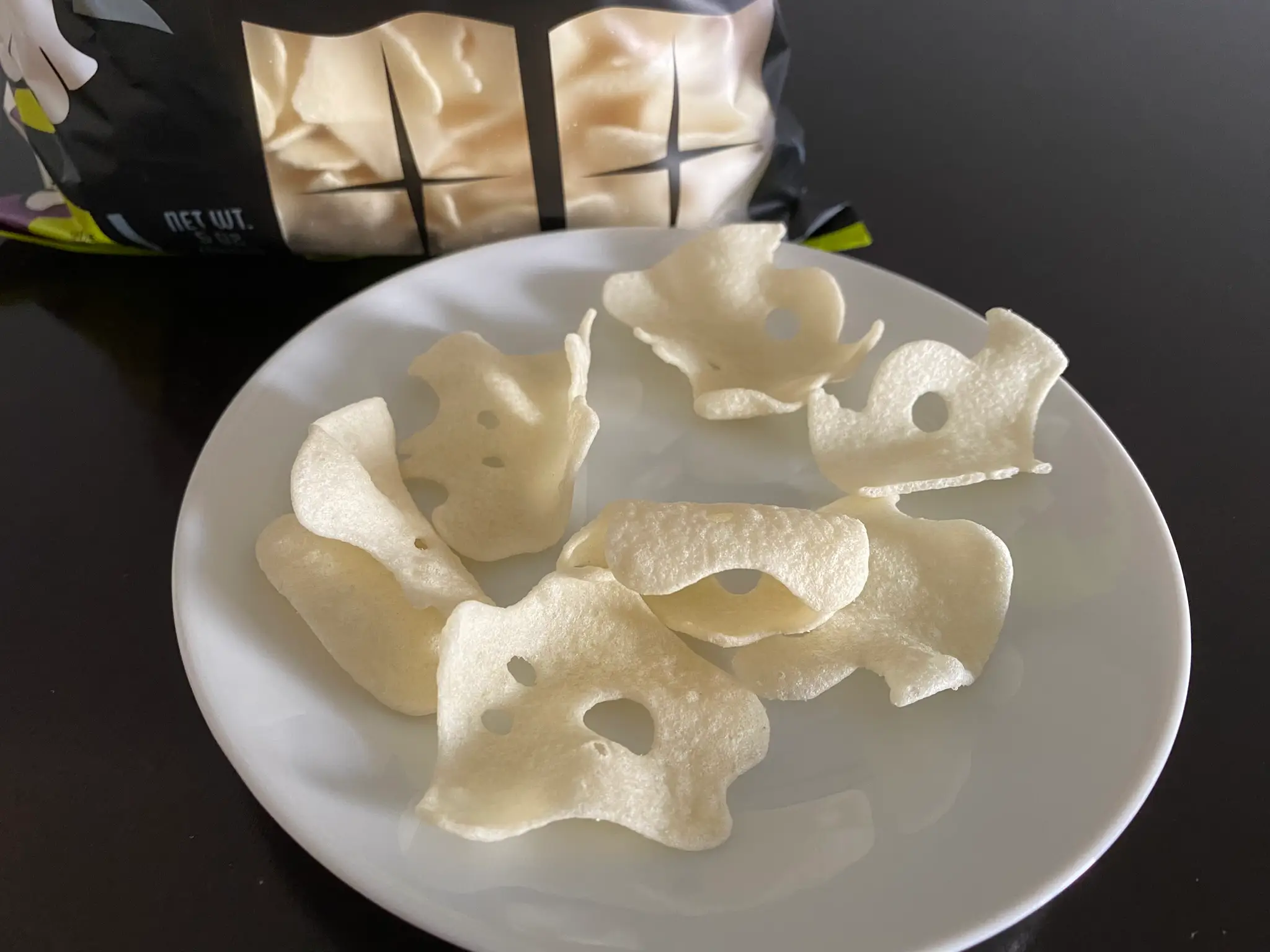White crispy potato chips with ghost faces in them on plate