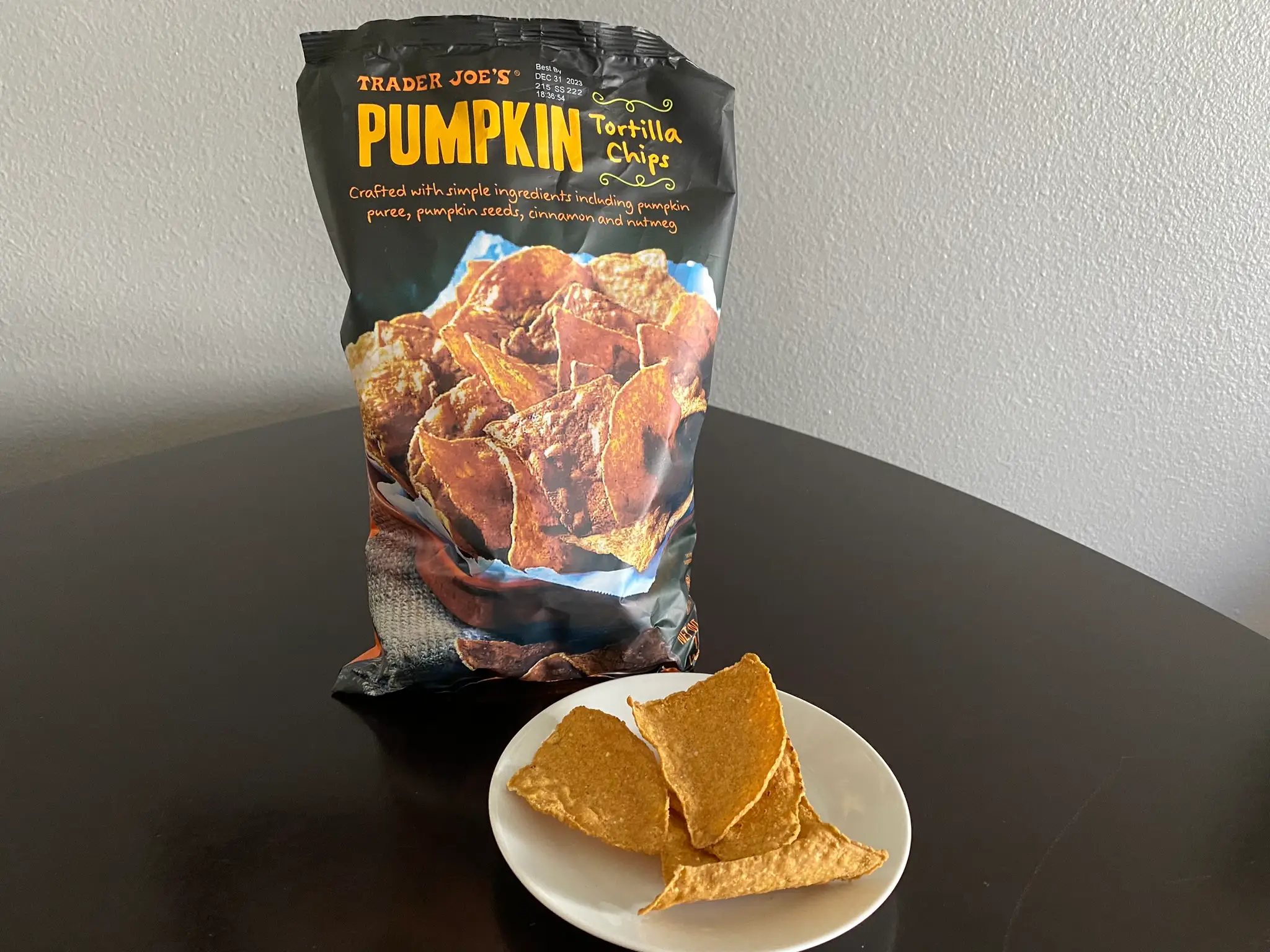 Bag of Trader Joe's pumpkin tortilla chips with plate of chips in front of bag