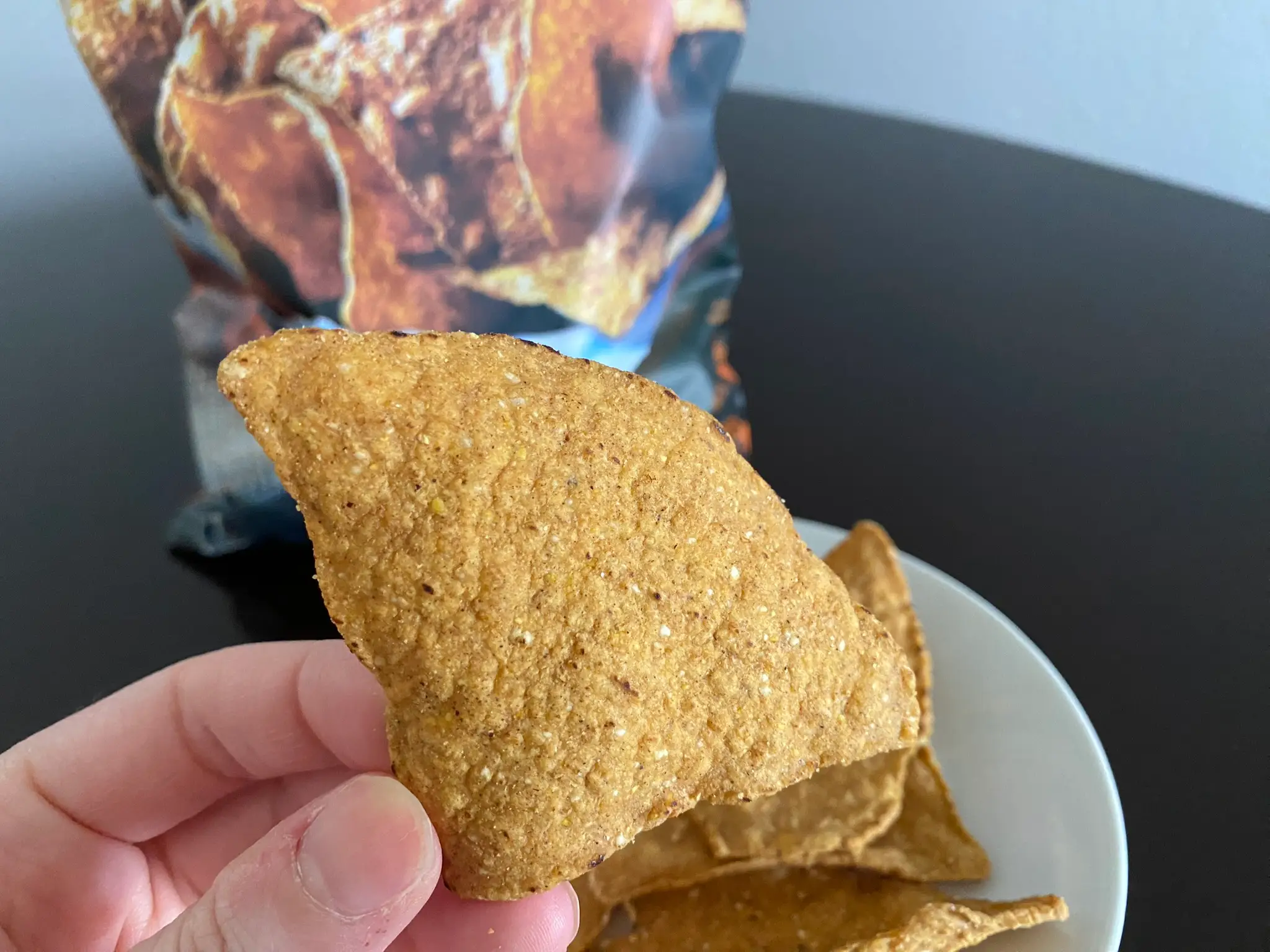 Author holding Trader Joe's pumpkin tortilla chip in front of bag