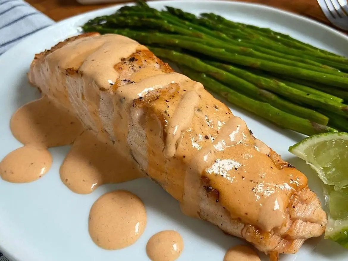 Salmon with red pepper aoili next to asparagus