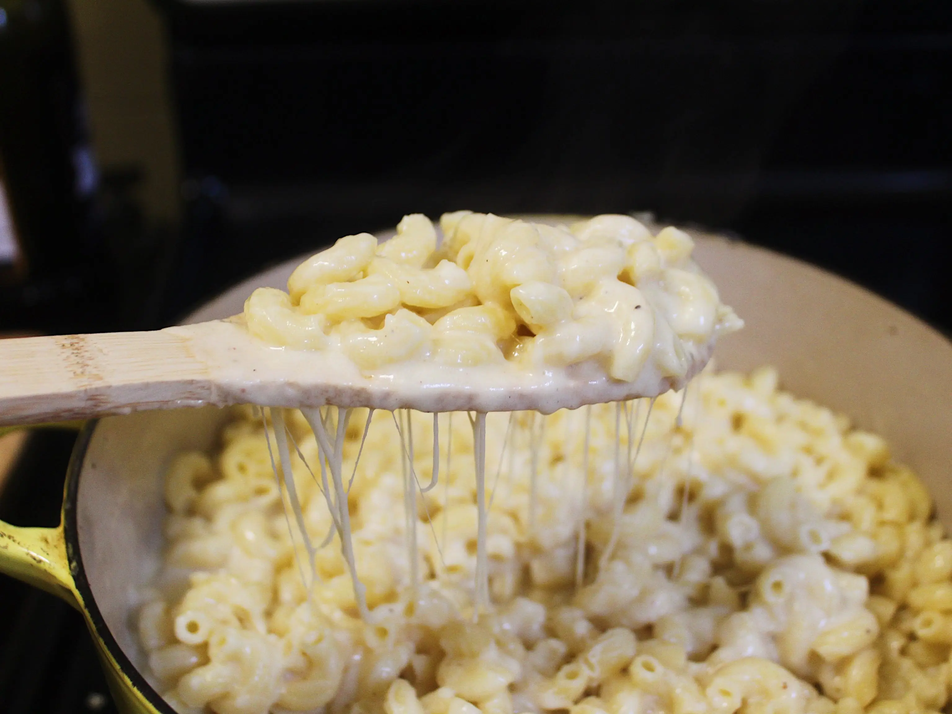 macaroni mixed with cheese sauce and a wooden spoon