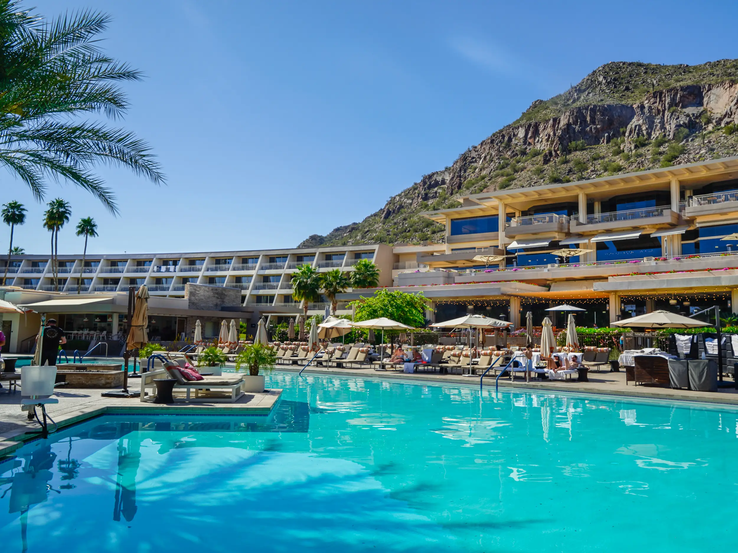 A resort pool in front of a mountain with blue skies