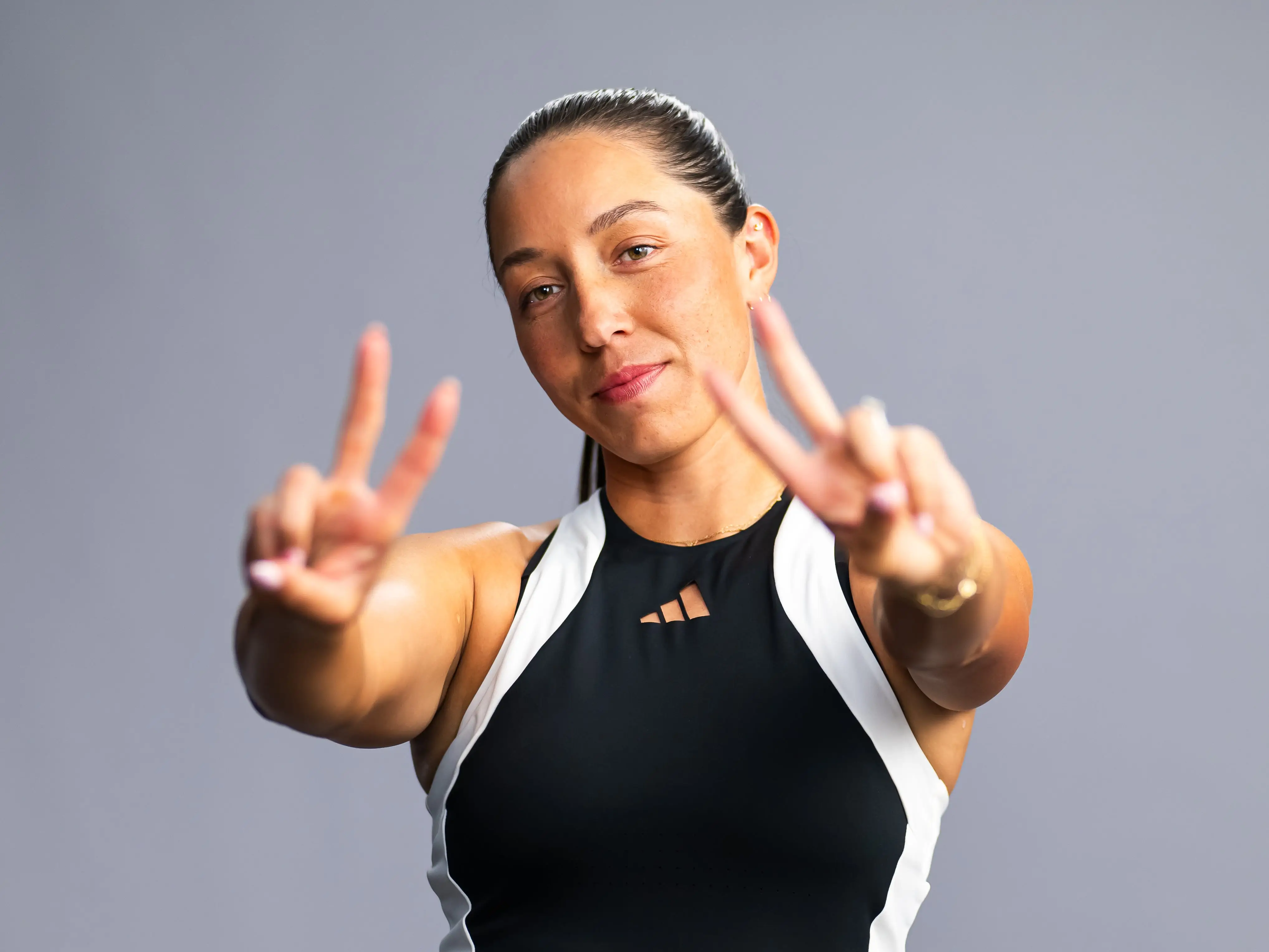 Jessica Pegula flashes two peace signs to the camera for a media shoot during the 2024 BNP Paribas Open.