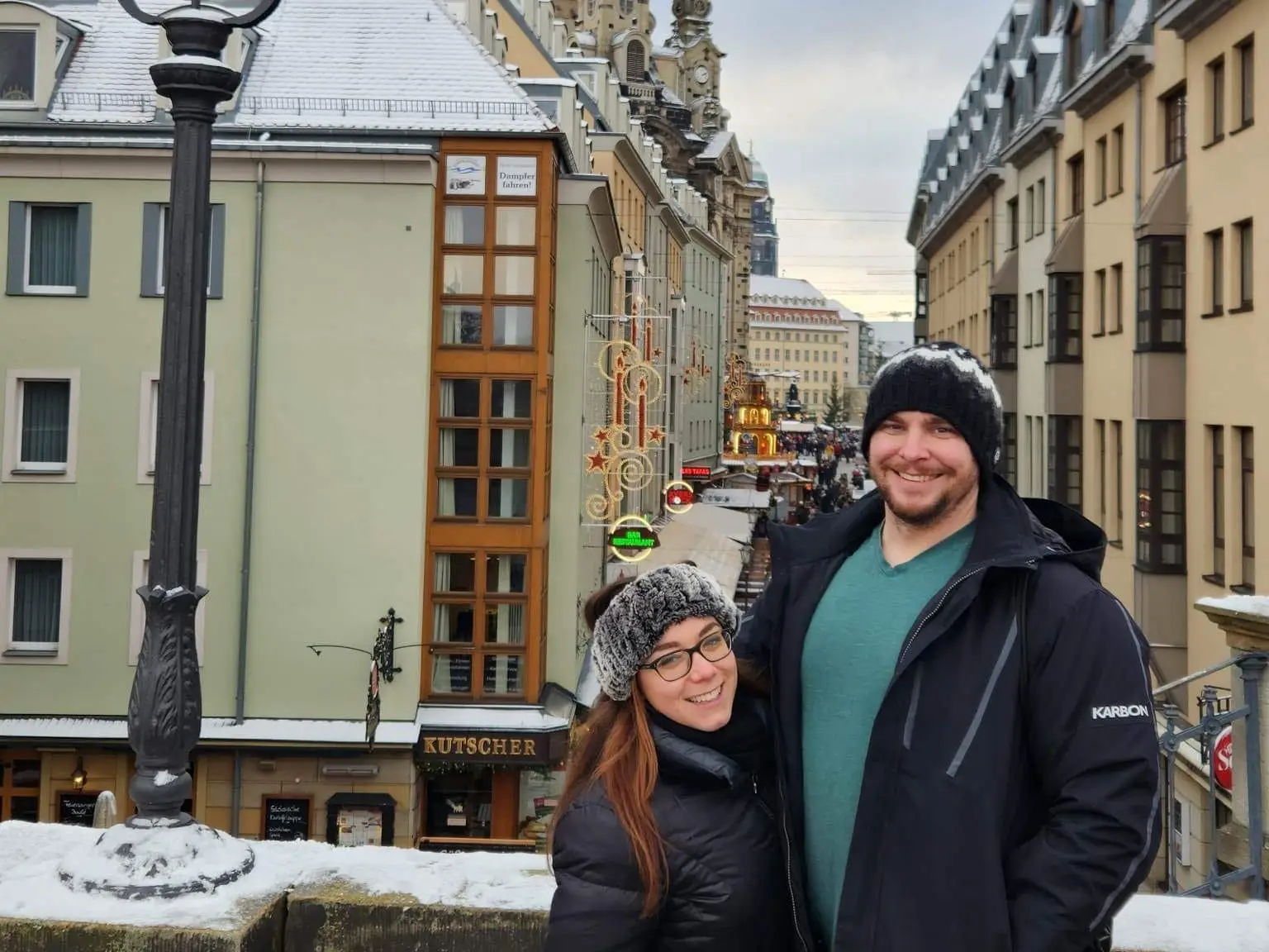 The author and her husband standing on a balcony in front of a snowy German downtown street.