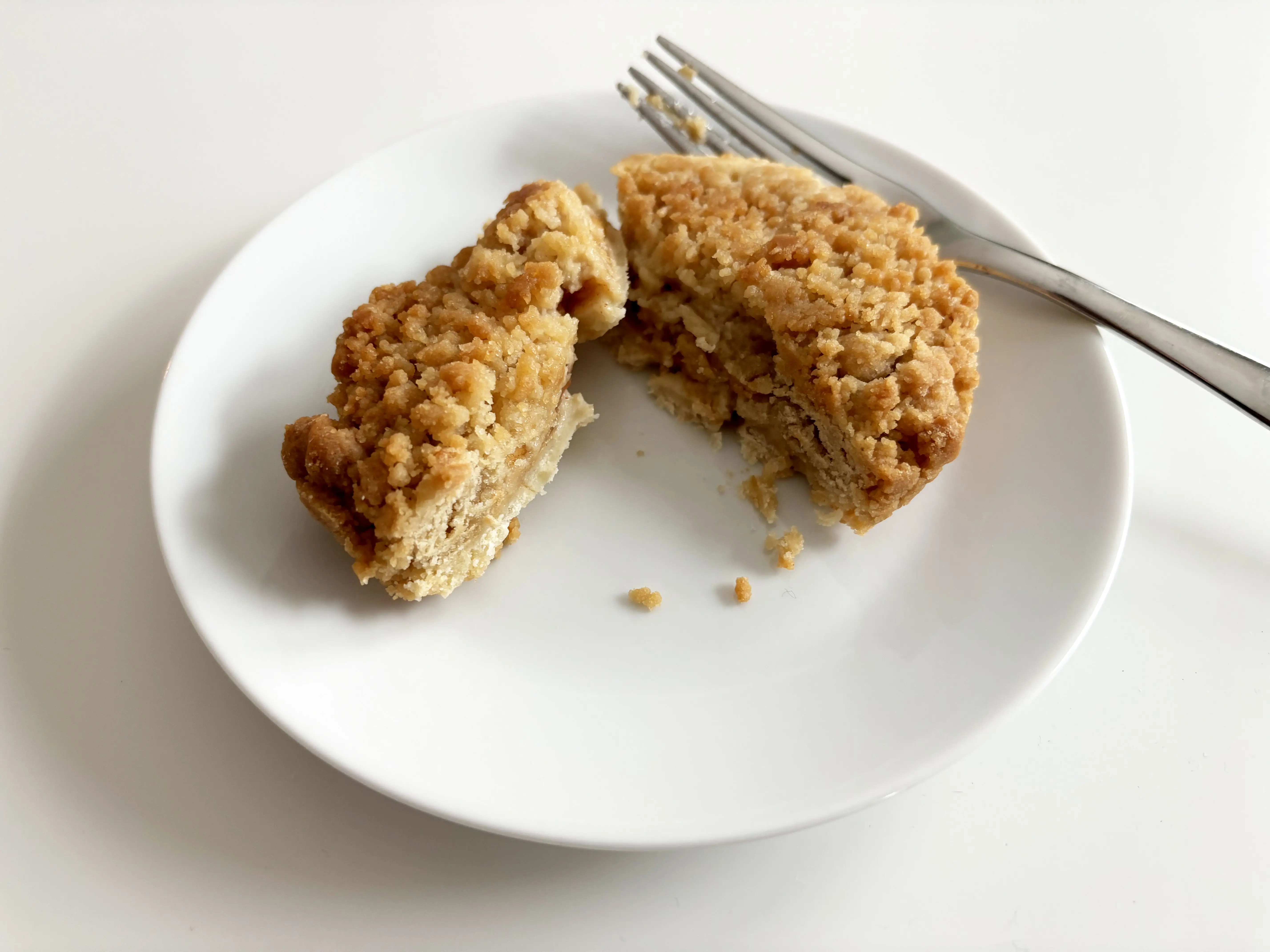 A Teeny Tiny apple pie from Trader Joe's sliced in half on a white plate with a fork.