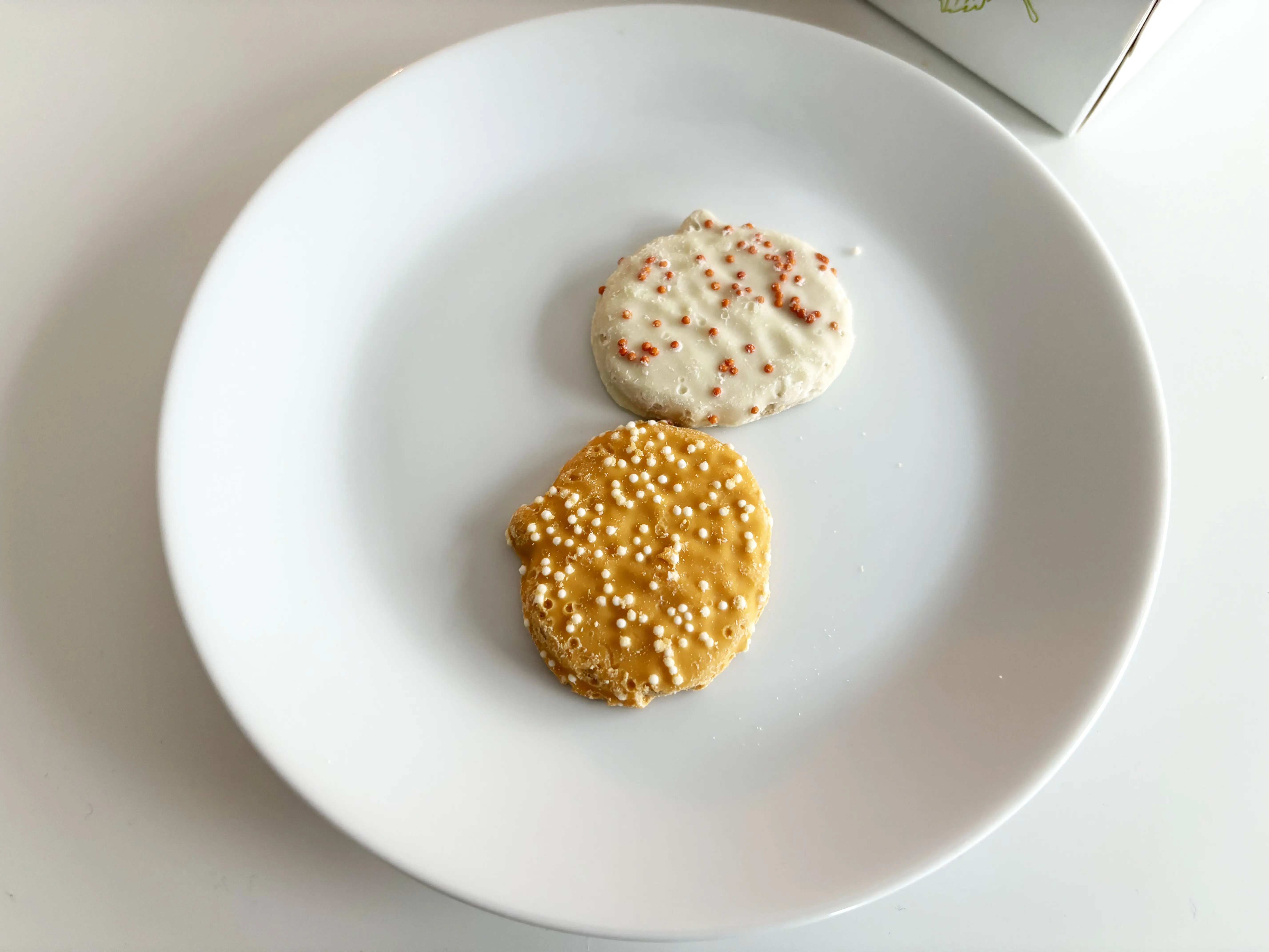 Orange and white pumpkin-shaped cookies with sprinkles on a white plate.