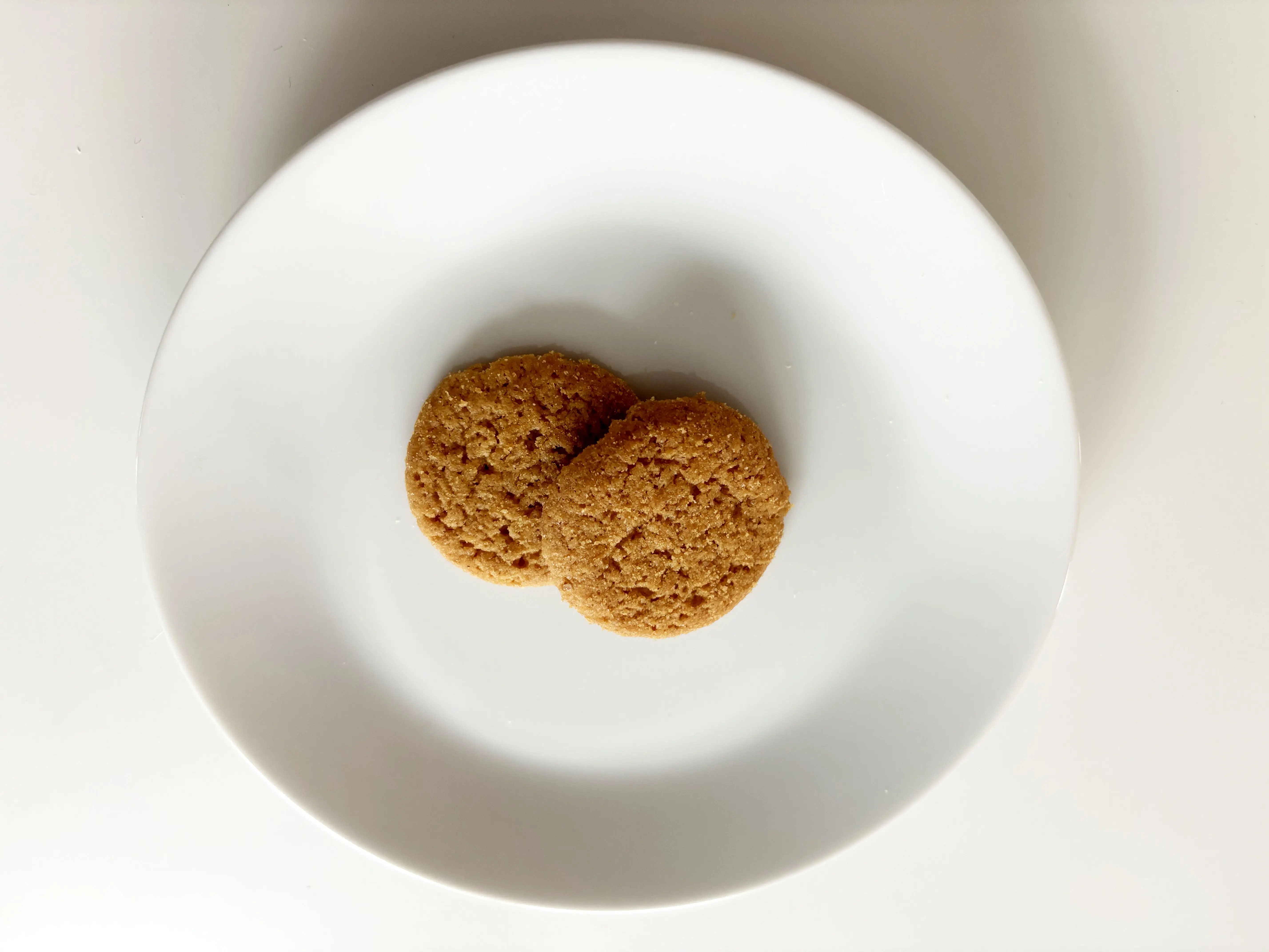 Two cookies from Trader Joe’s maple pancake snaps on a white plate.