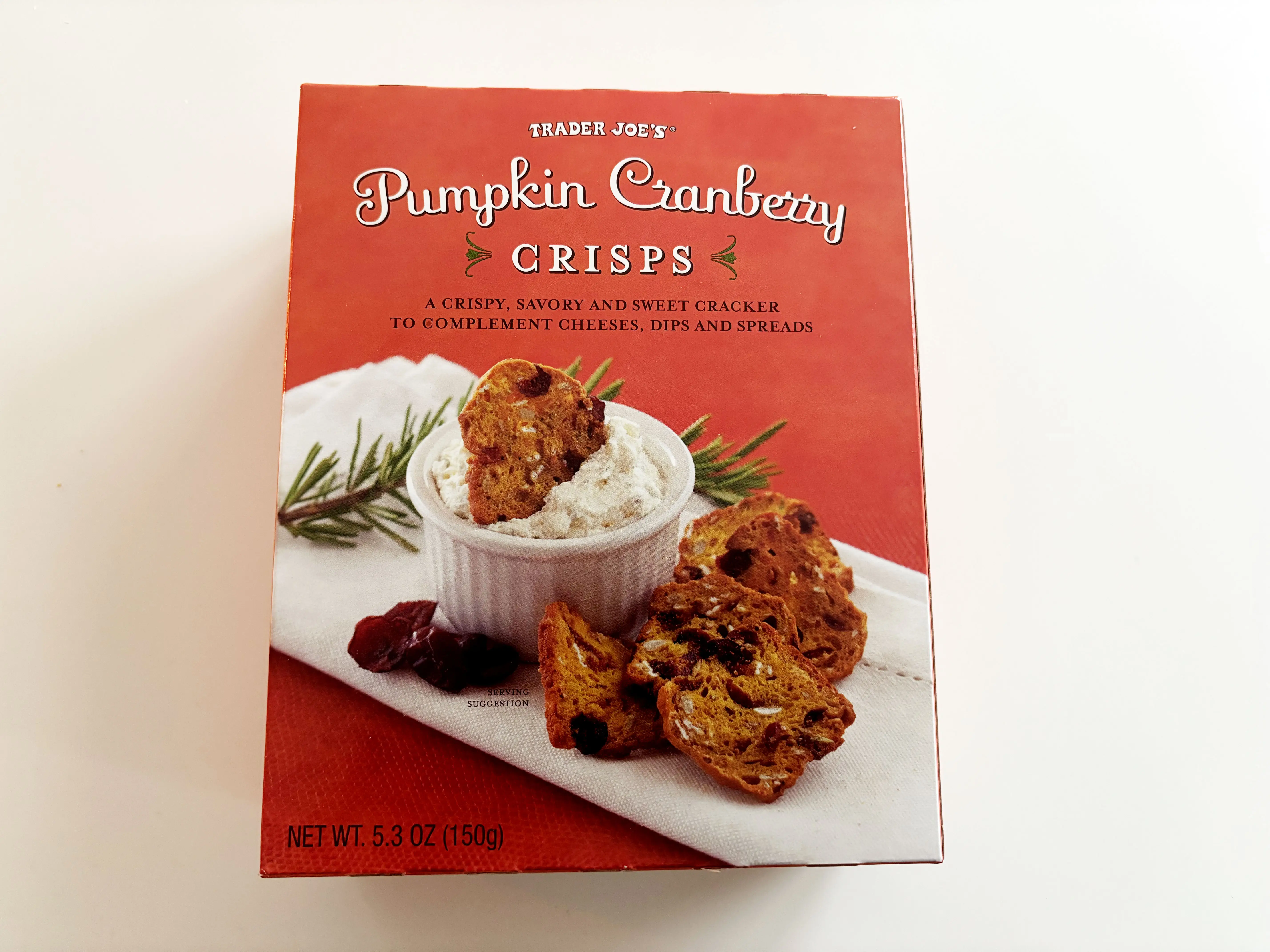 A red box of Trader Joe's pumpkin-cranberry crisps with the crackers on the front.