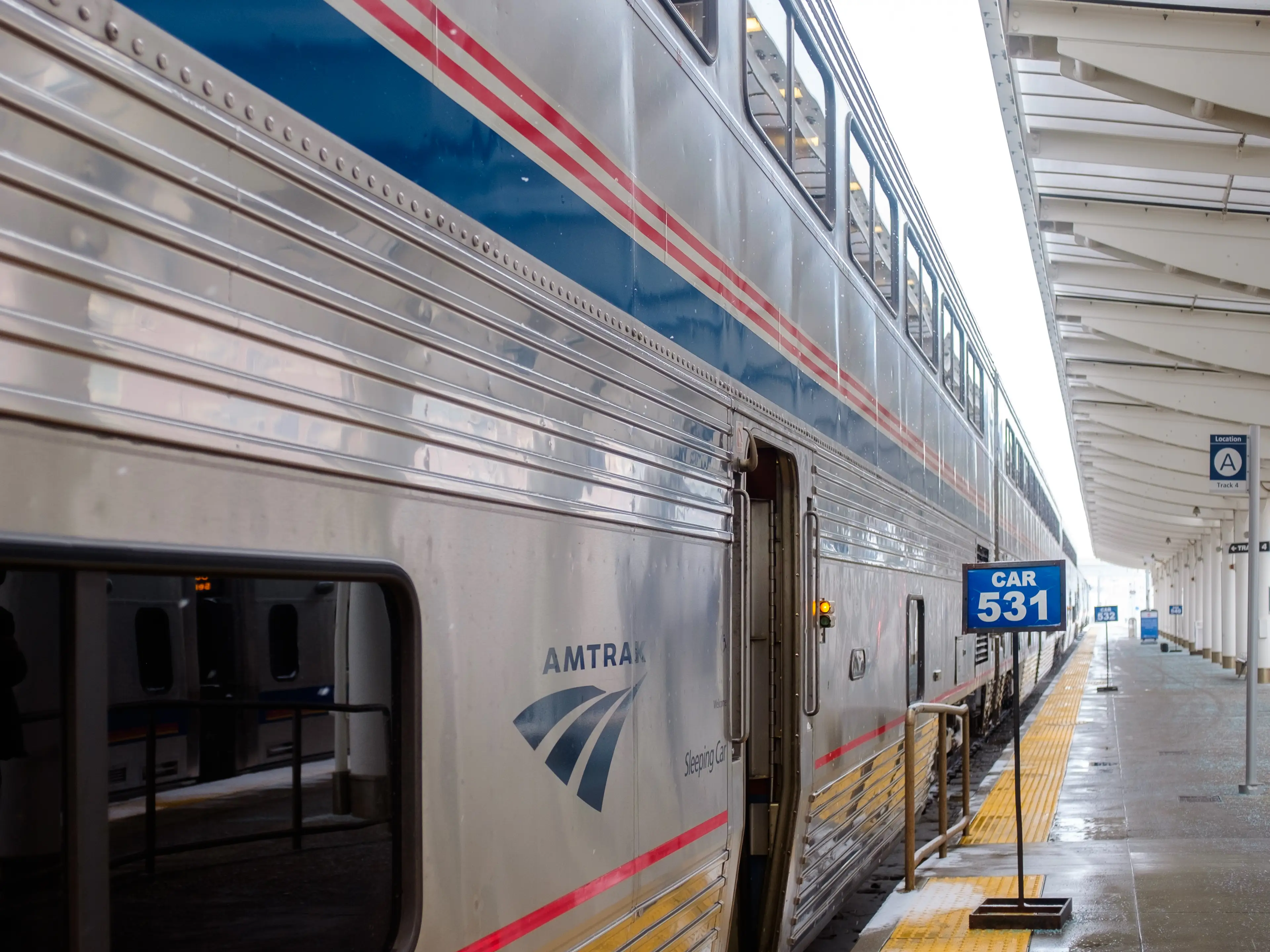 A parked double-decker Amtrak train on a platform with signs indicating each car number