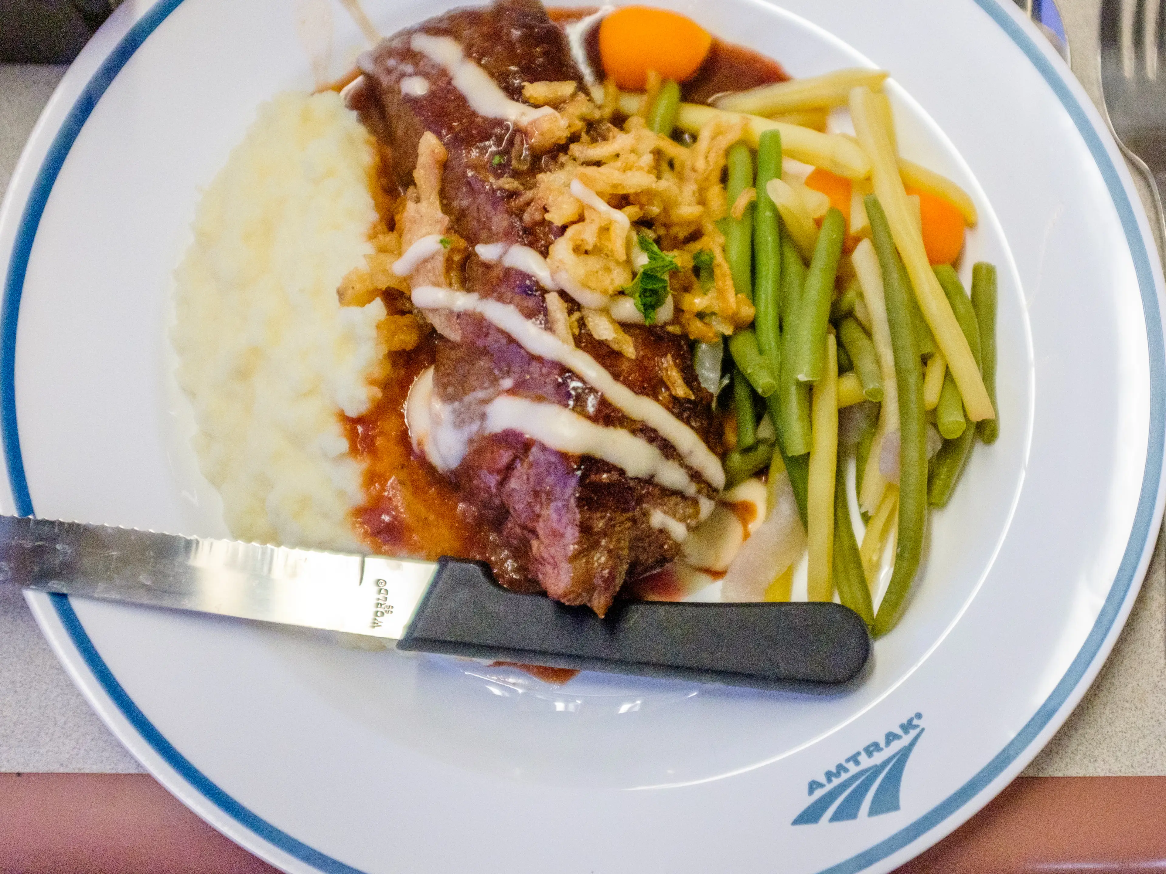 A white plate with meat, mashed potatoes, and vegetables on it.