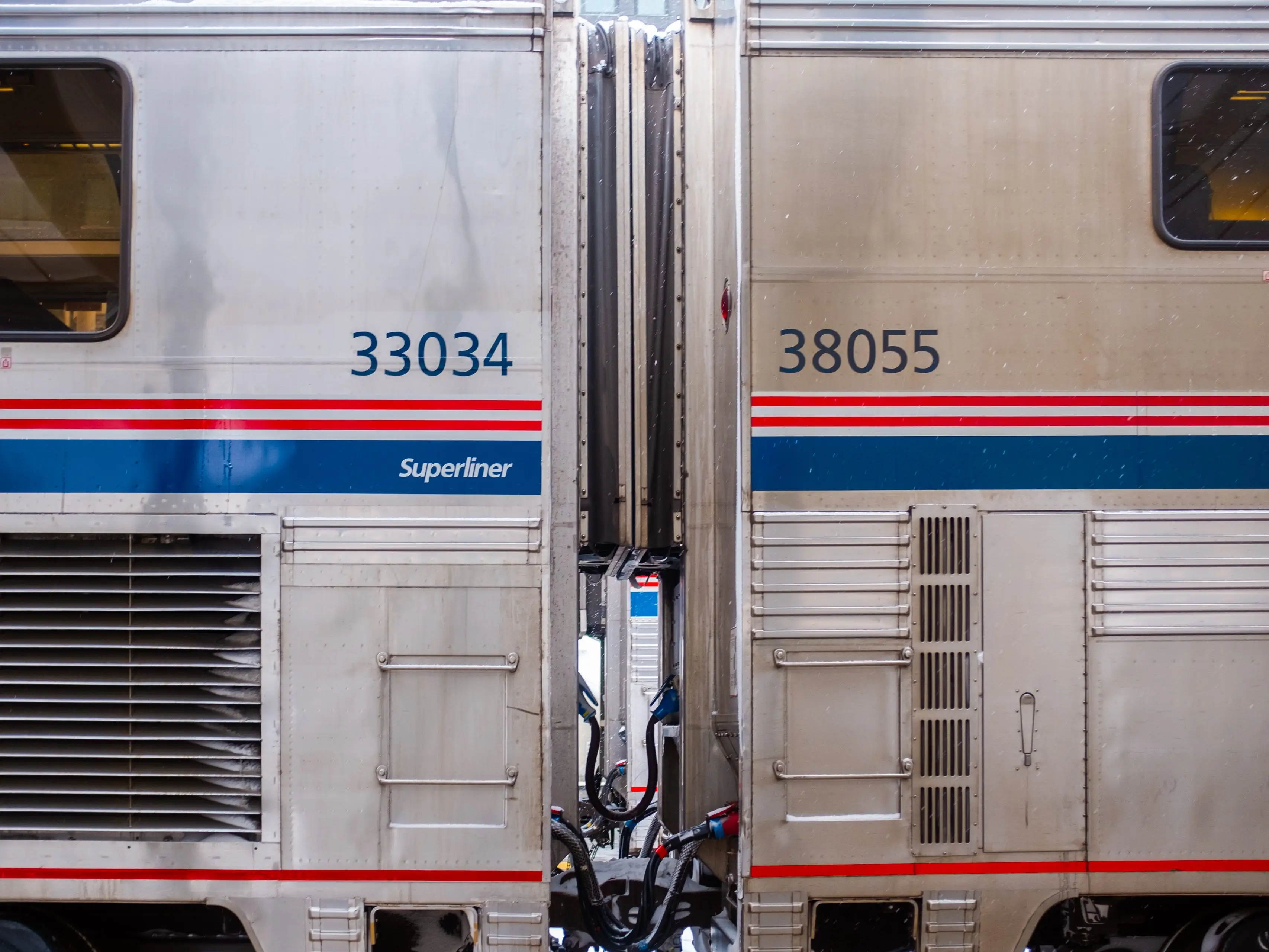 A close-up of two gray train cars with red and blue stripes
