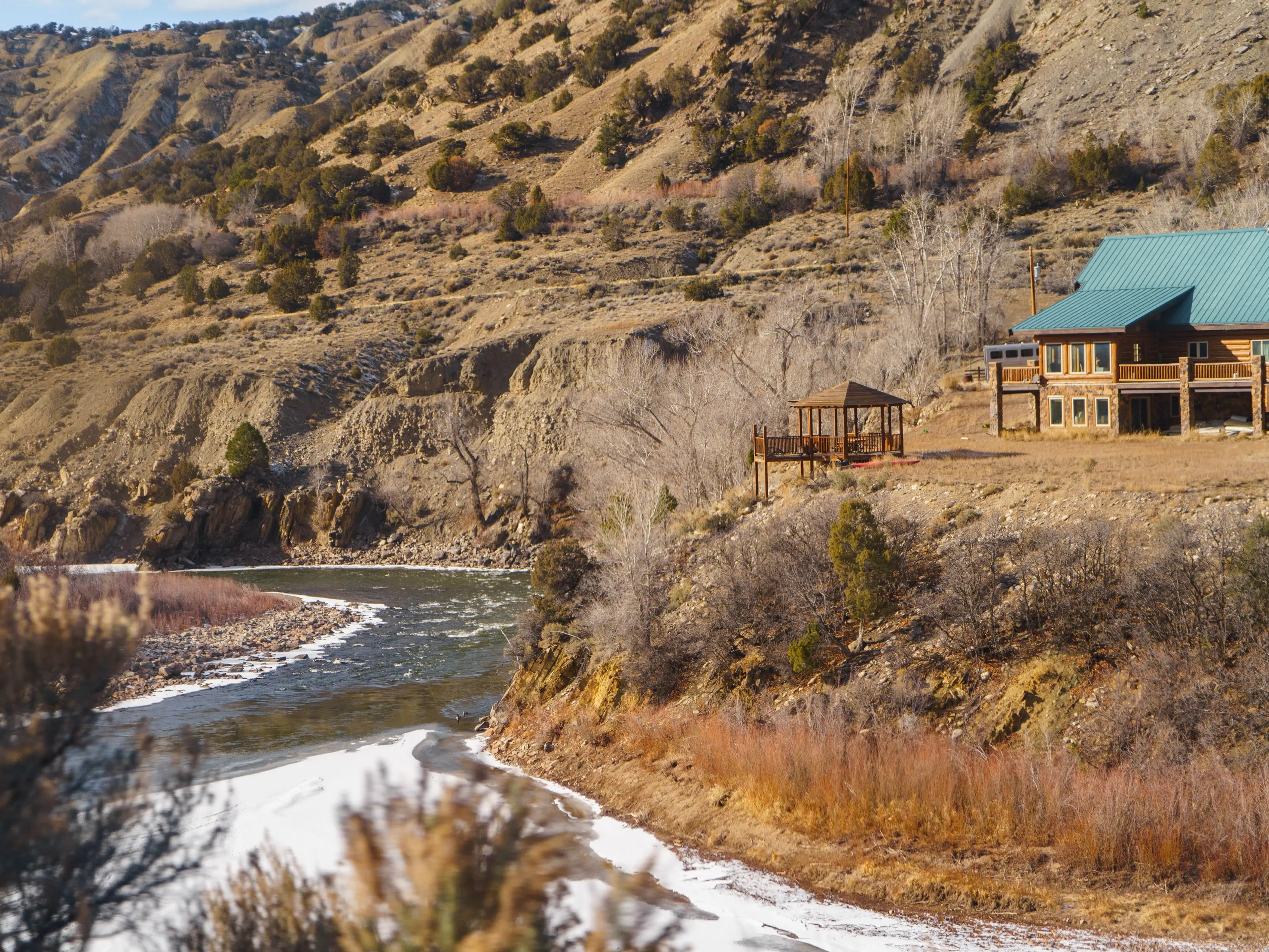 A river runs west of a home with mountains in the background