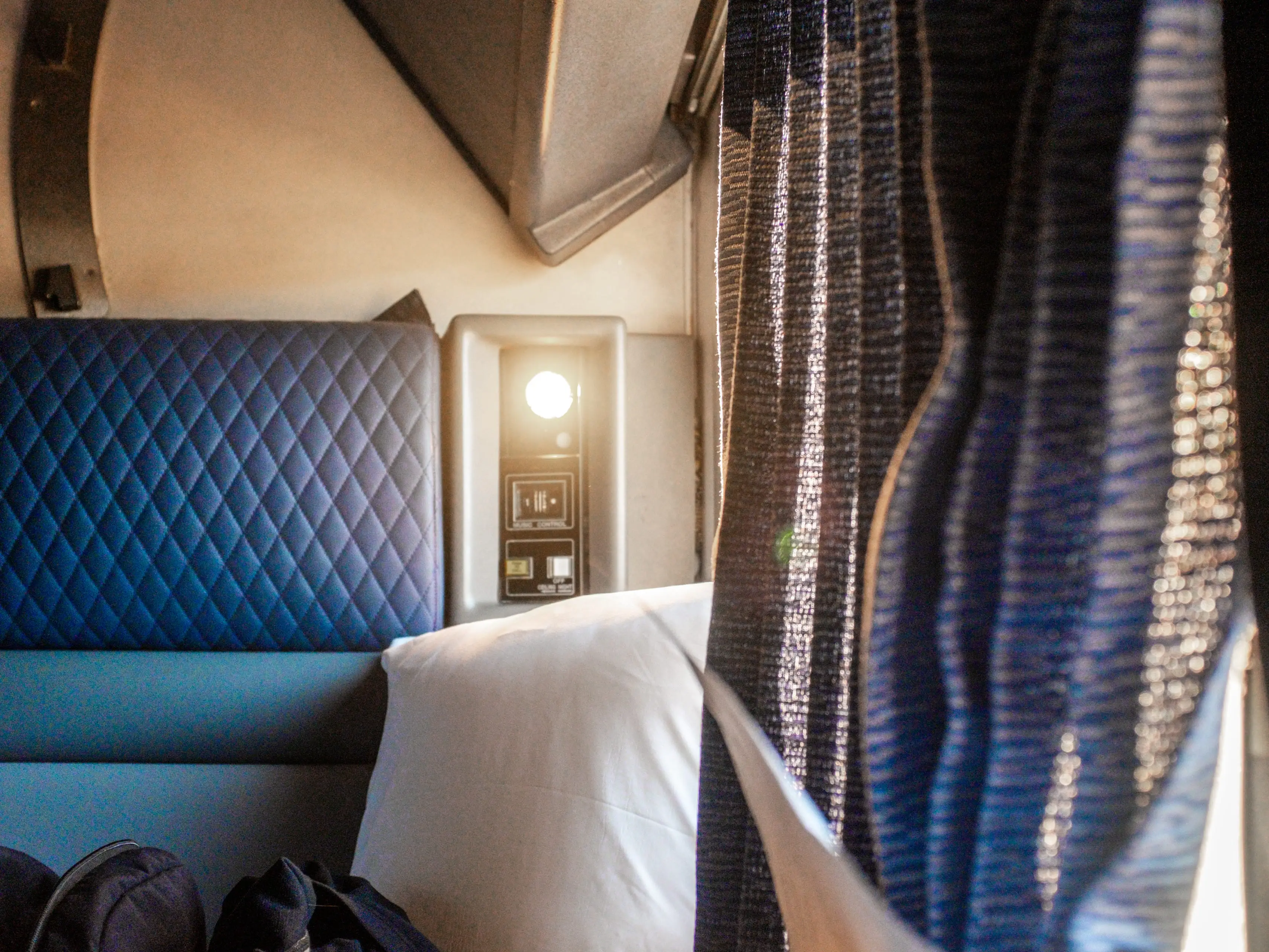 Inside a train cabin with curtains on the right and a chair on the left