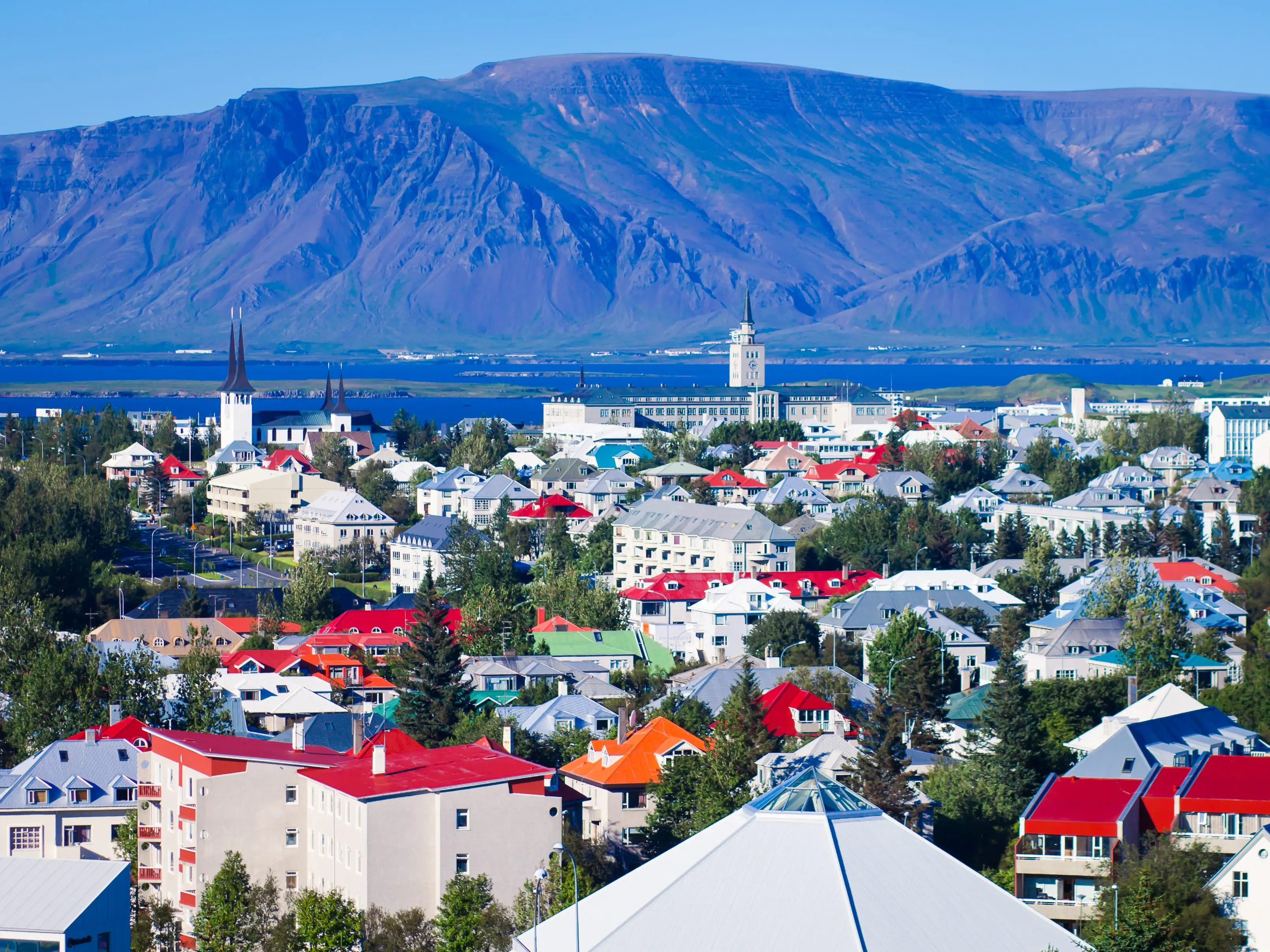 A city with mountains and a body of water in the background.