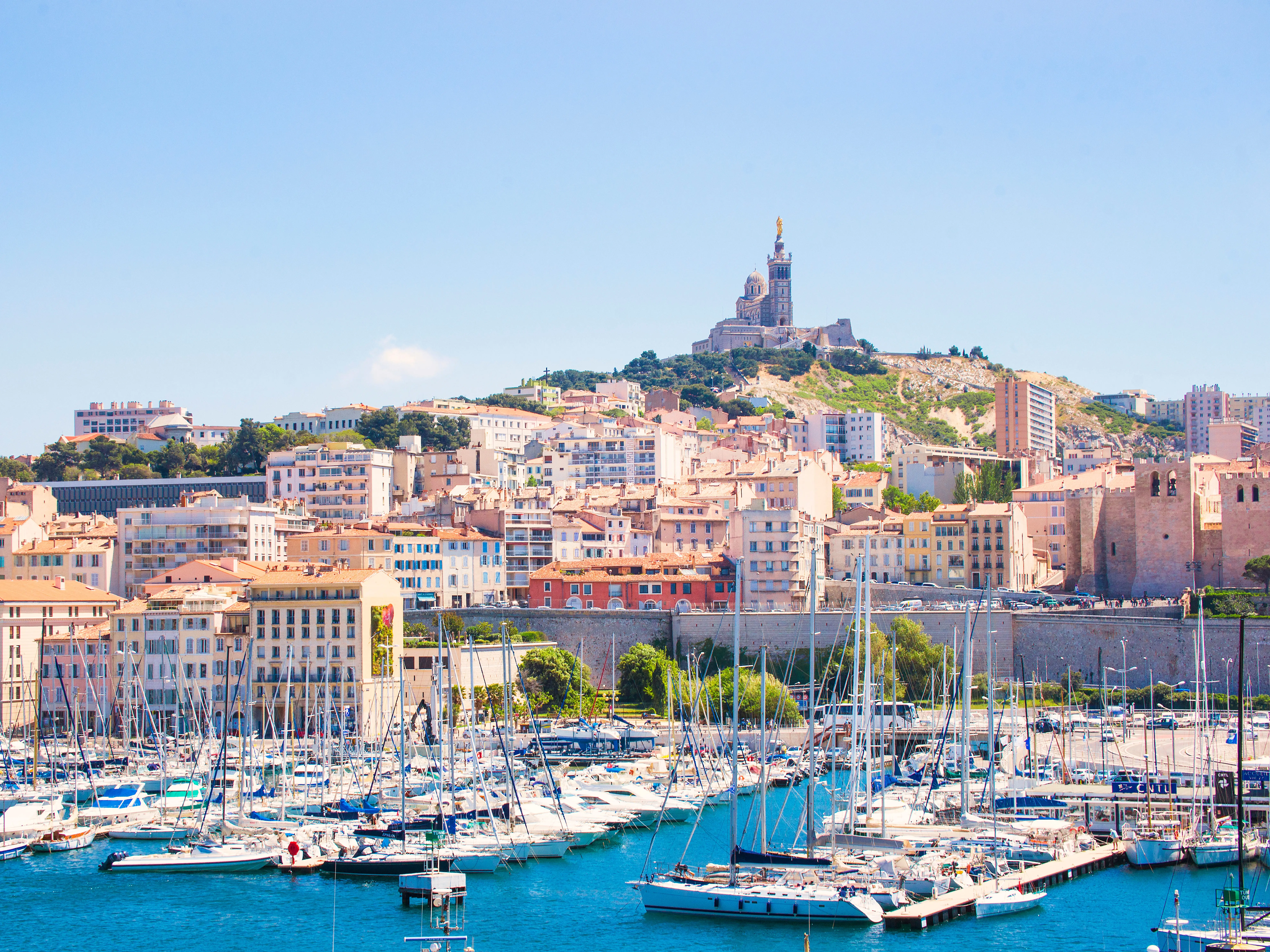 Hundreds of boats docked in a harbor, with a city and a church on a hill behind them.
