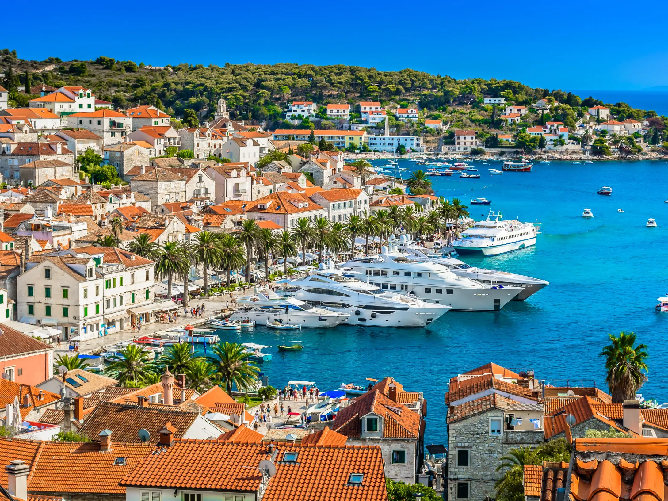 An aerial view of a coastal city, with yachts docked in the water.