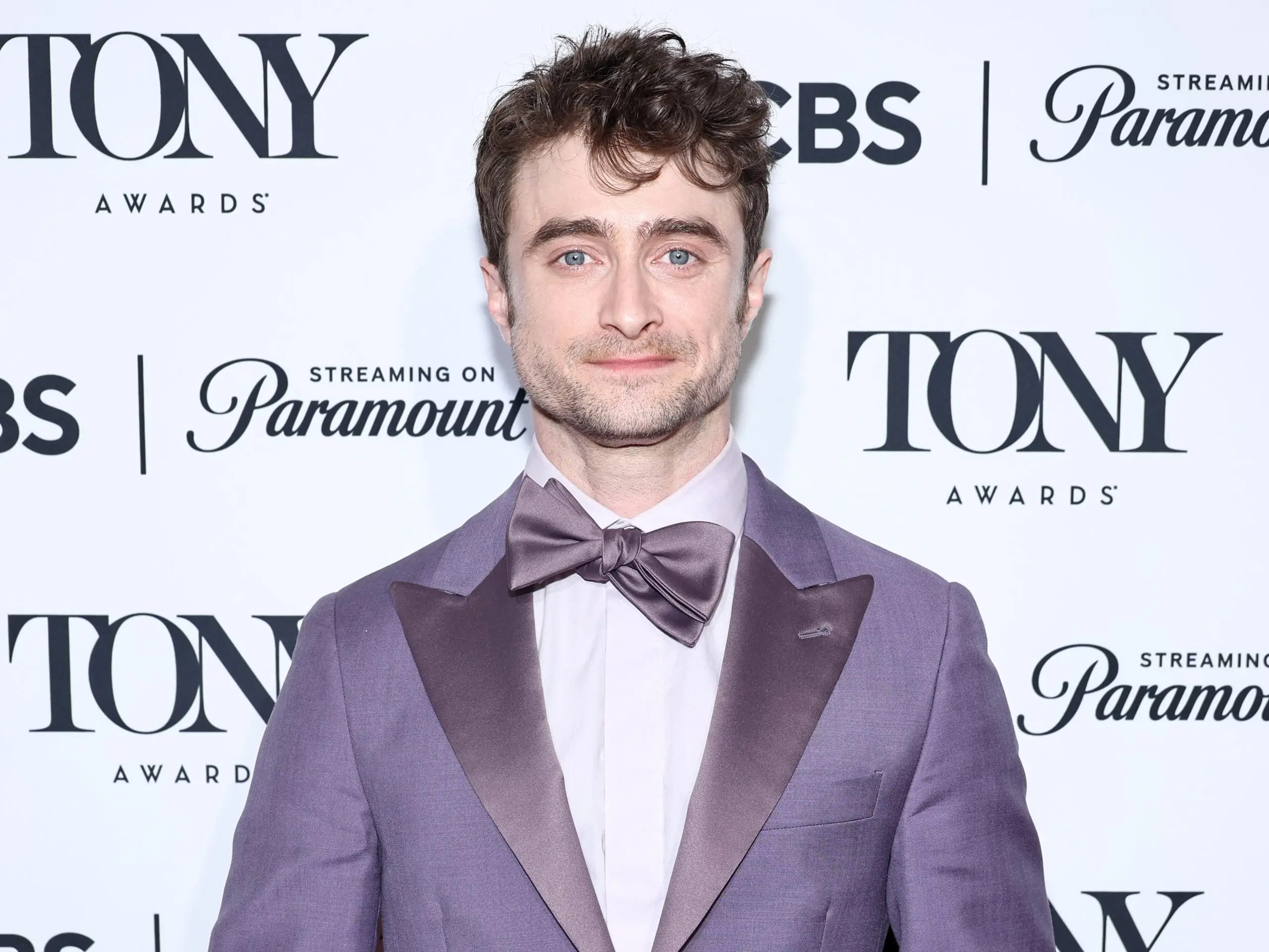 daniel radcliffe on the red carpet at the tony awards holding a tony statue