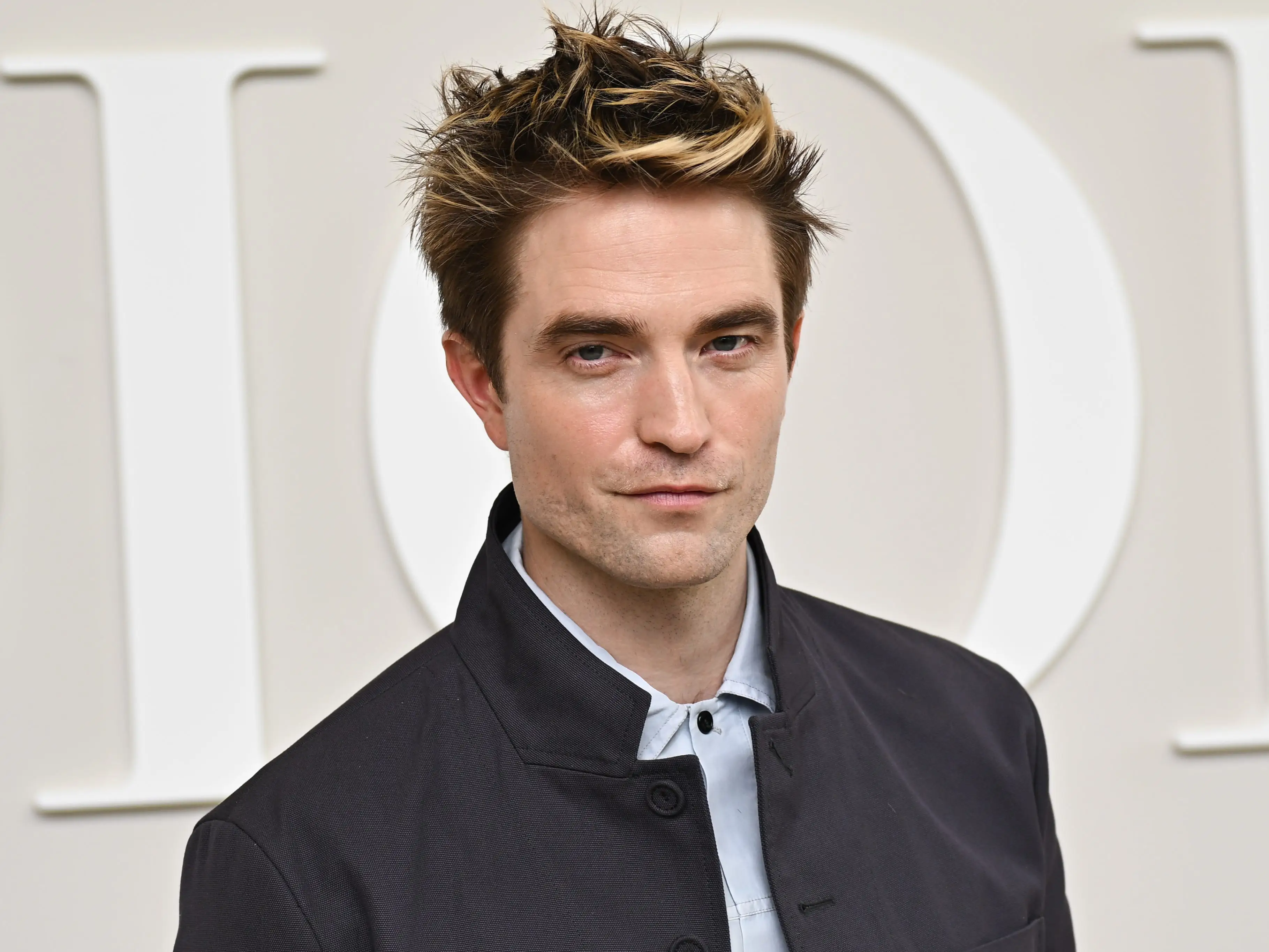 robert pattinson posing on the red carpet at a dior fashion week event