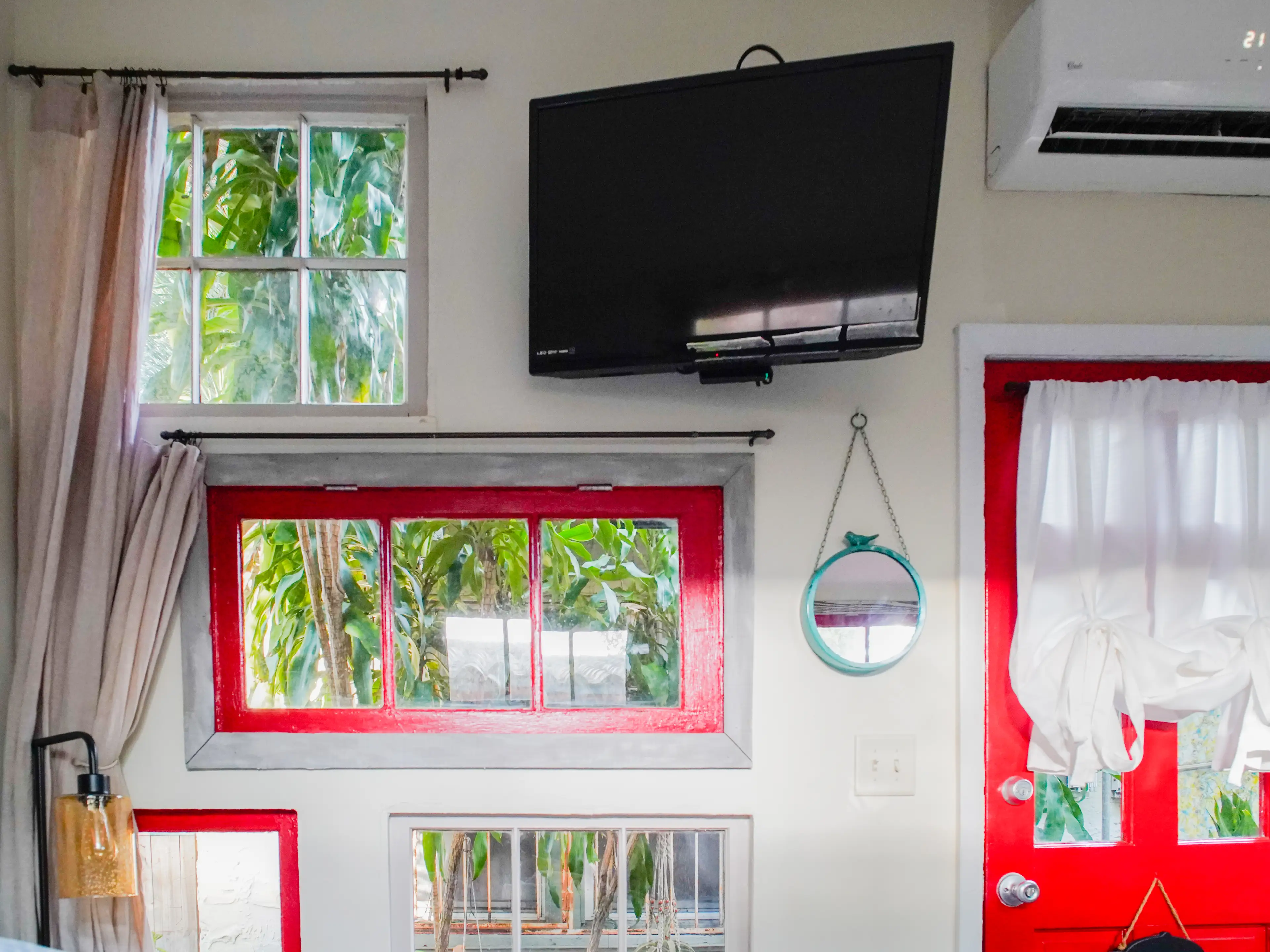 Windows on the wall next to a hanging TV in the tiny home