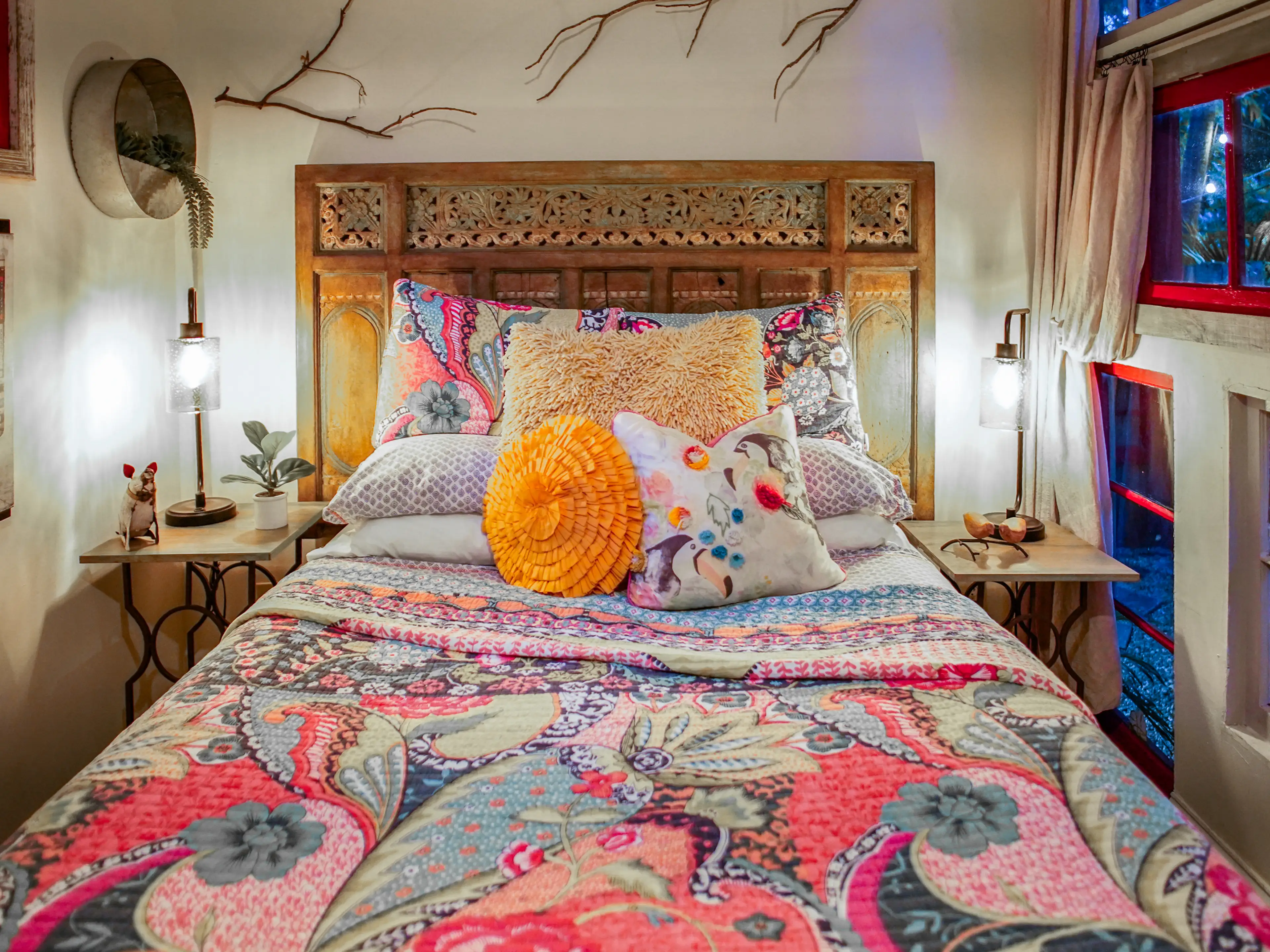 A bed with a wood headboard topped with a pink quilt in the tiny home