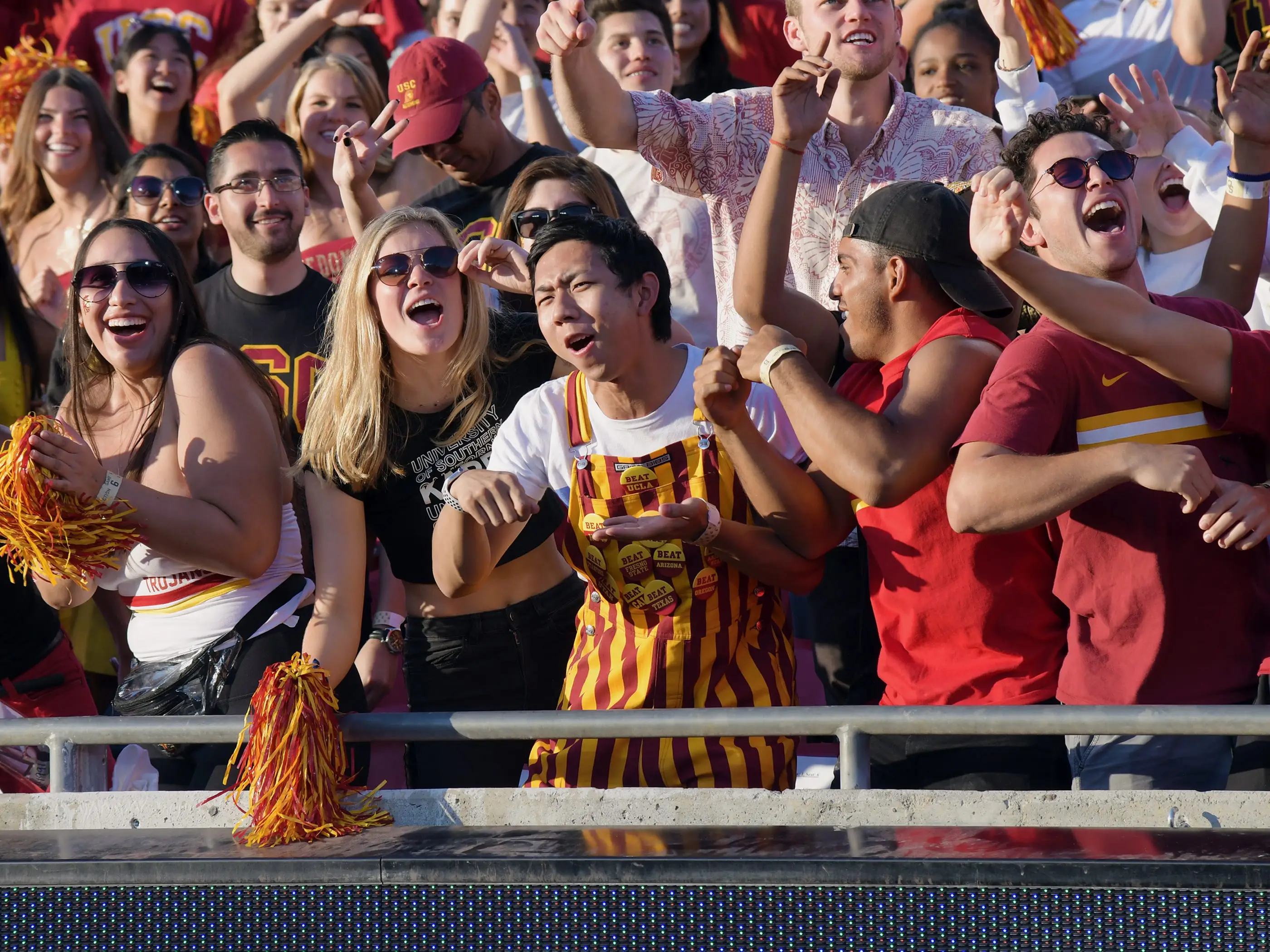 Students at the front row of a sports game, cheering.