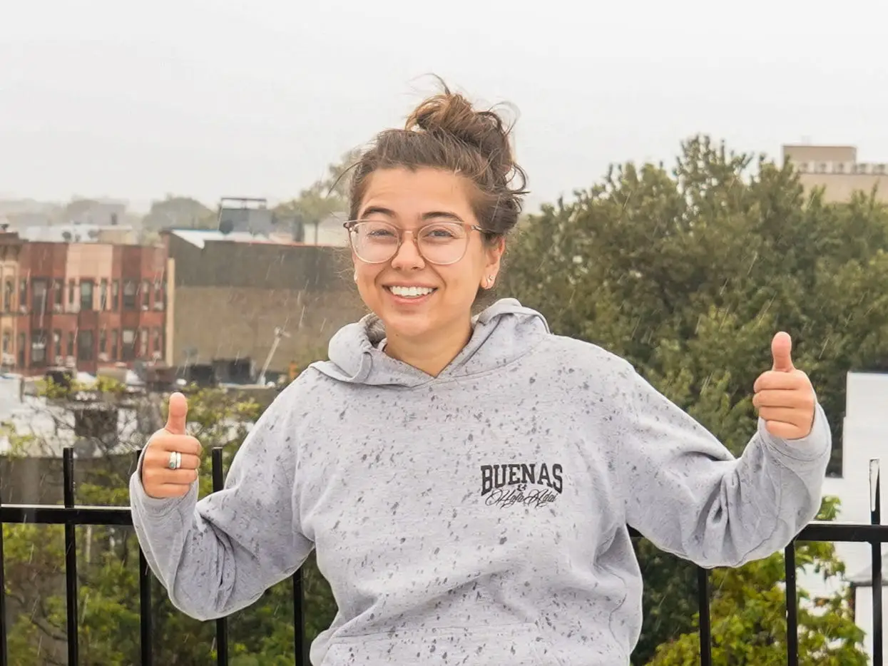 The author smiles with her thumbs up on a rainy day in Brooklyn