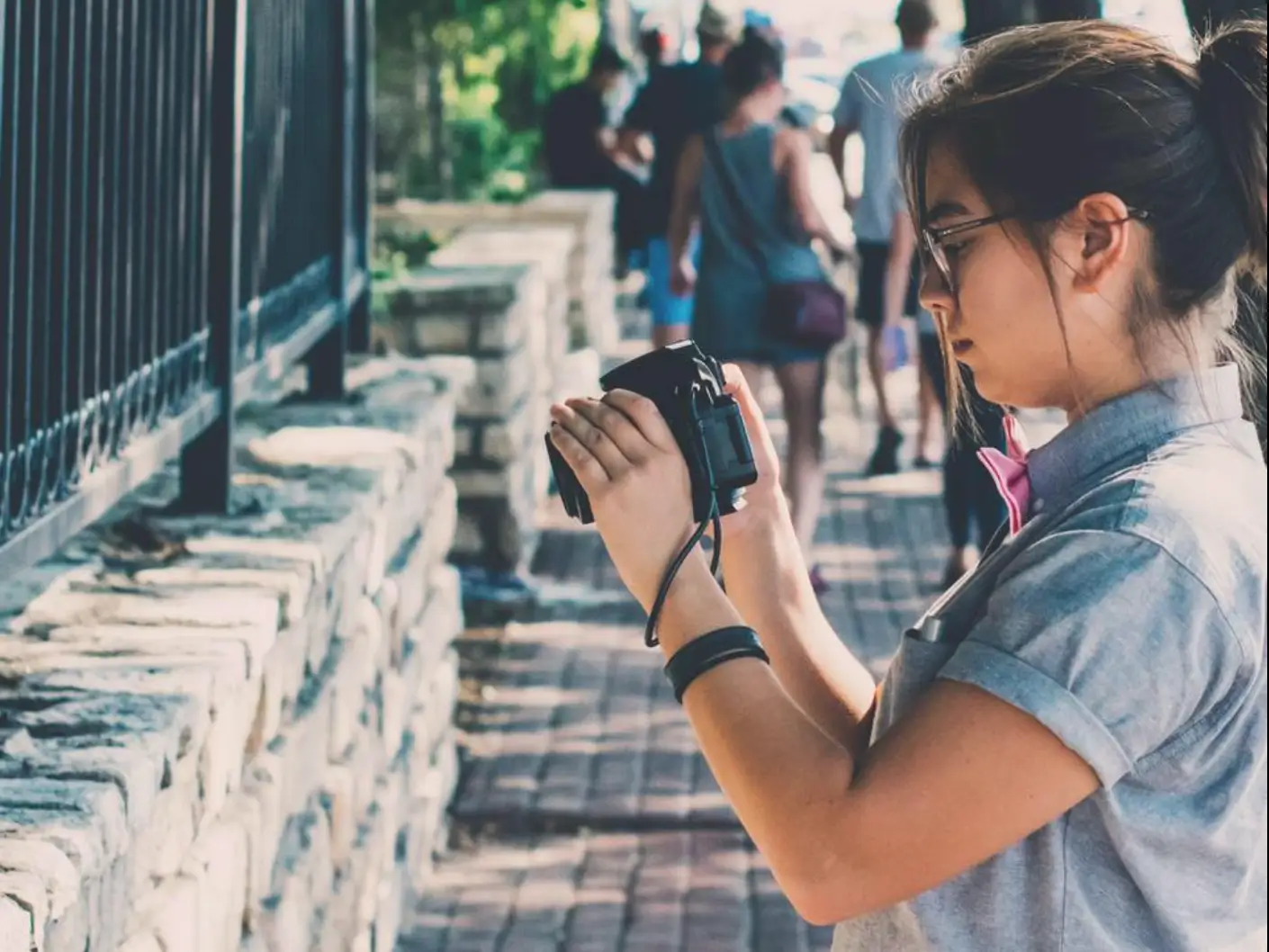 The author takes a photo on the street in Austin Texas with trees and pedestrians behind her