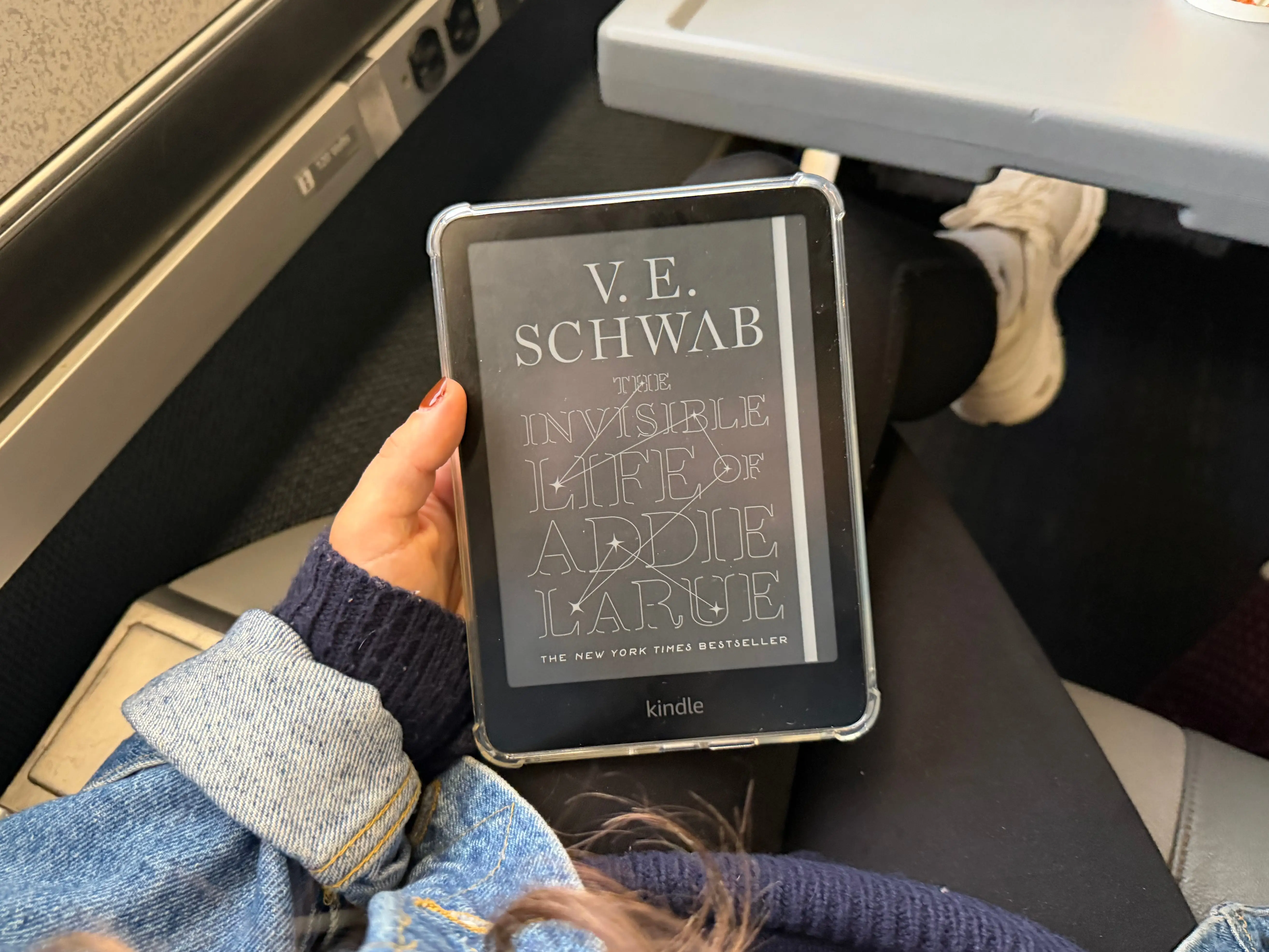 A hand holding a Kindle on an Amtrak ride.